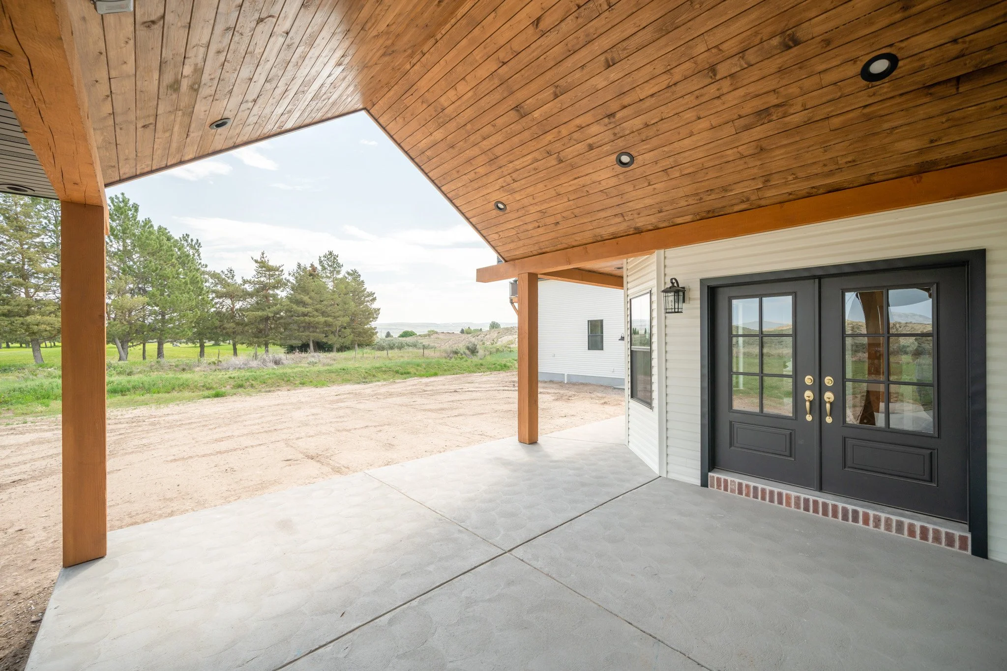 Covered rear patio with timber columns and wood ceiling — JAB Construction’s Modern Rustic custom home in Idaho Falls, Idaho.