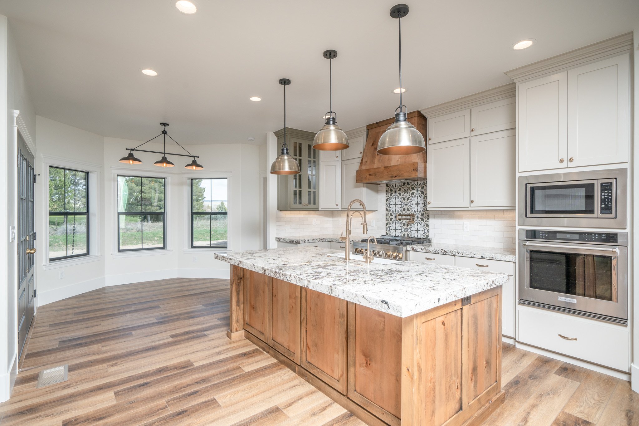 Kitchen with a wood island, light countertops and pendant lights — JAB Construction’s Modern Rustic custom home in Idaho Falls, Idaho.
