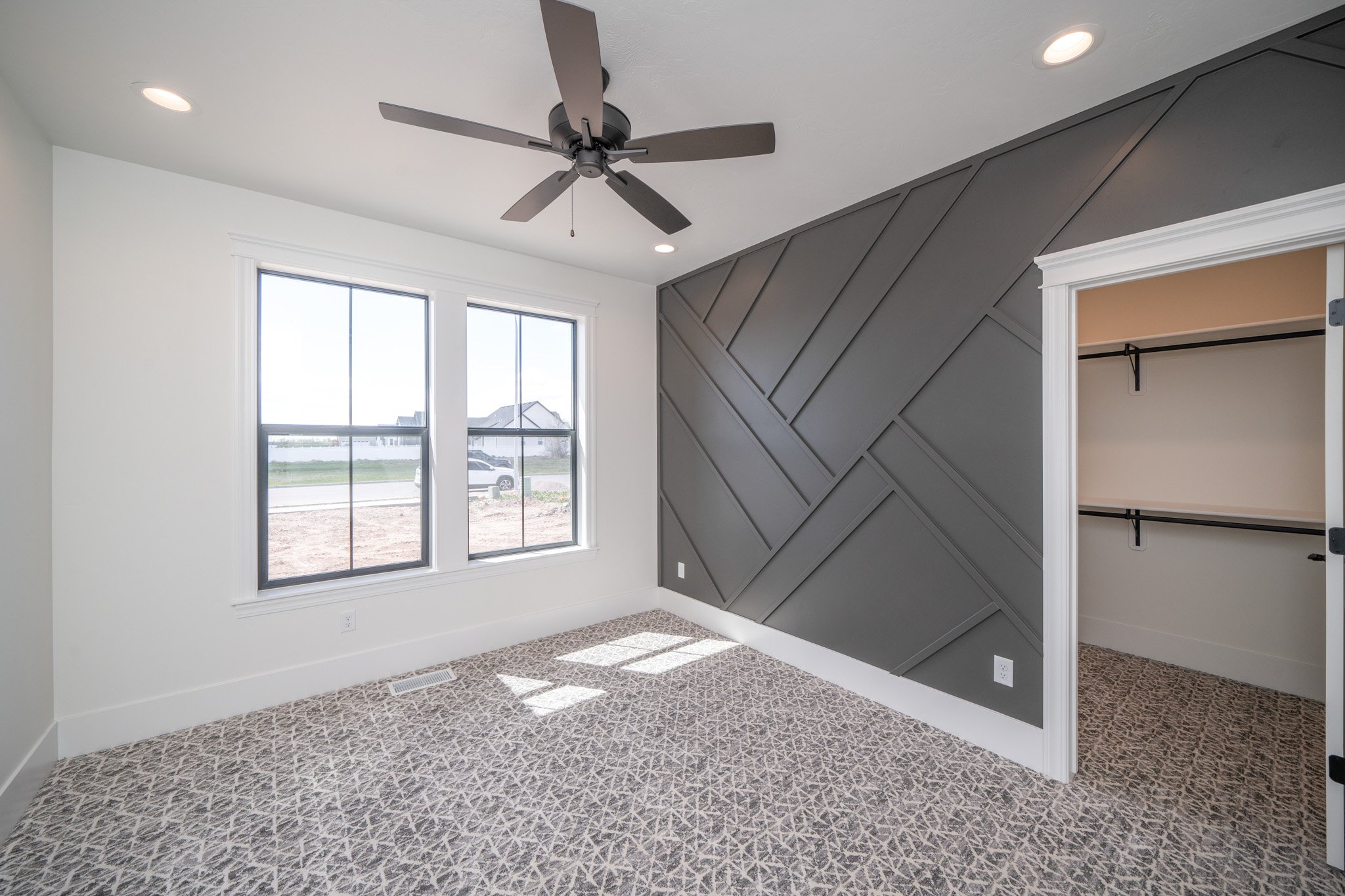 Bedroom with a geometric accent wall and large windows — JAB Construction’s Modern Rustic custom home in Idaho Falls, Idaho.