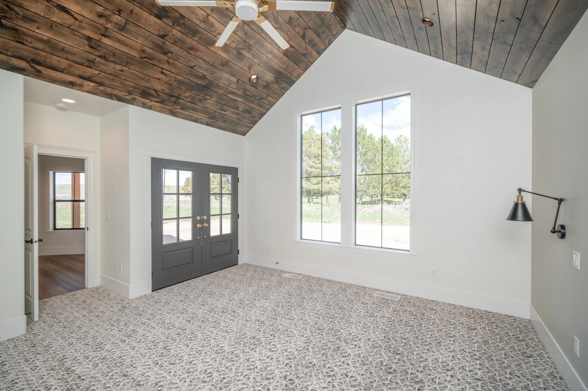Tall-ceilinged room with large windows and glass doors — JAB Construction’s Modern Rustic custom home in Idaho Falls, Idaho.