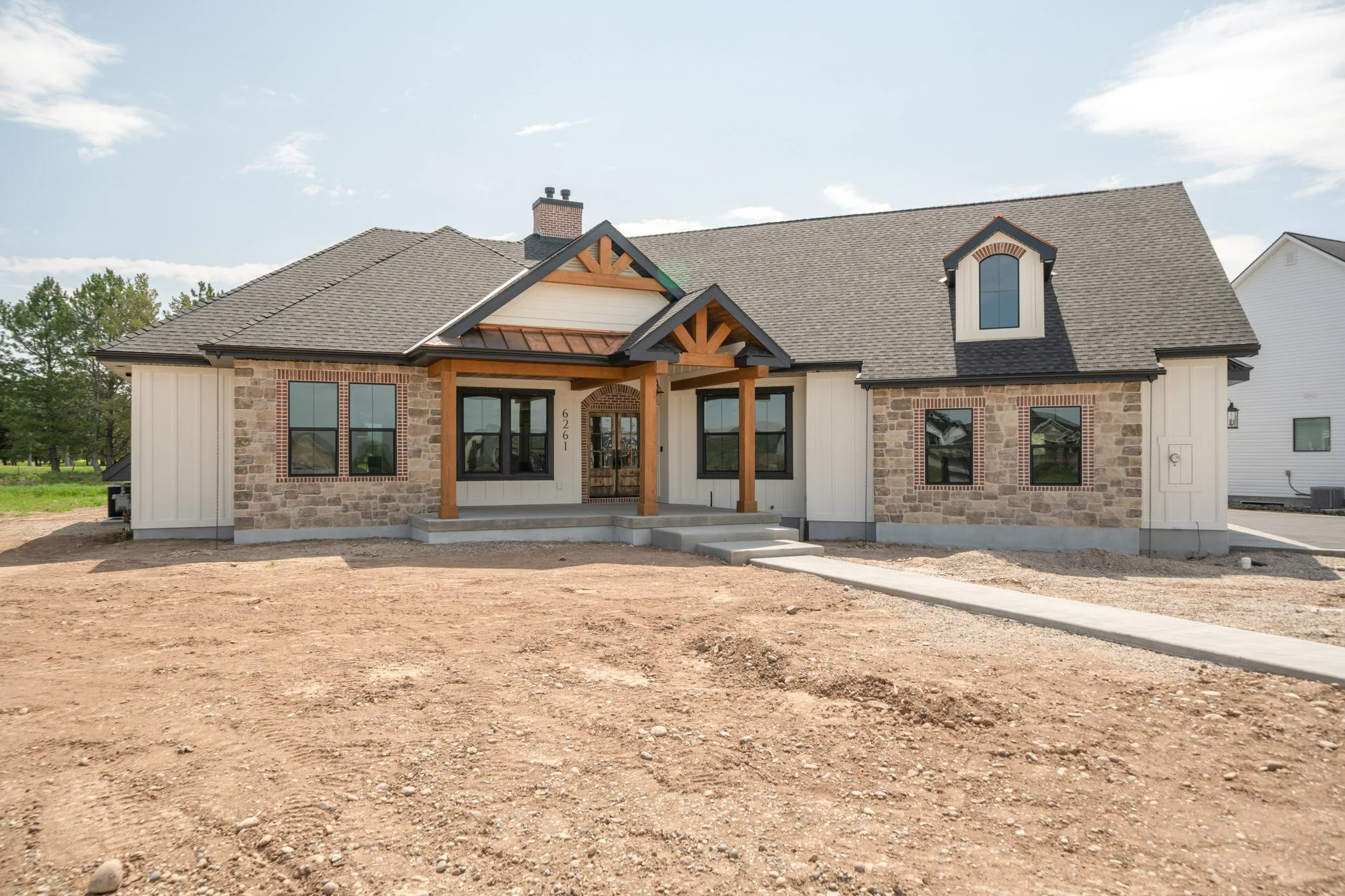 Front exterior with brick accents, timber detailing and a covered entrance — JAB Construction’s Modern Rustic custom home in Idaho Falls, Idaho.