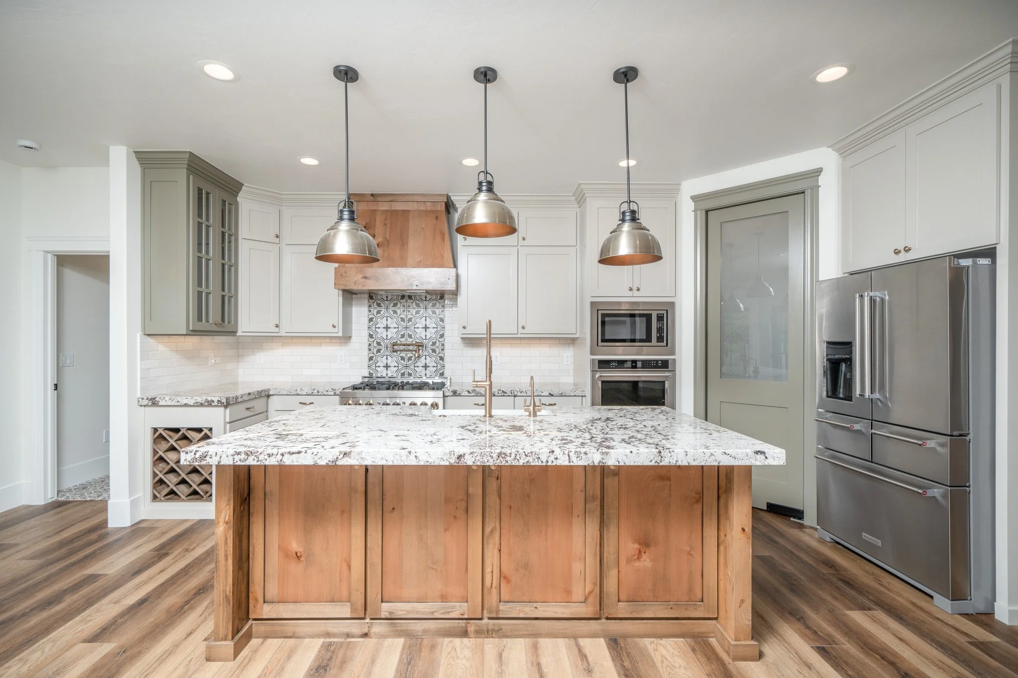 Kitchen island facing a range hood and white cabinetry — JAB Construction’s Modern Rustic custom home in Idaho Falls, Idaho.