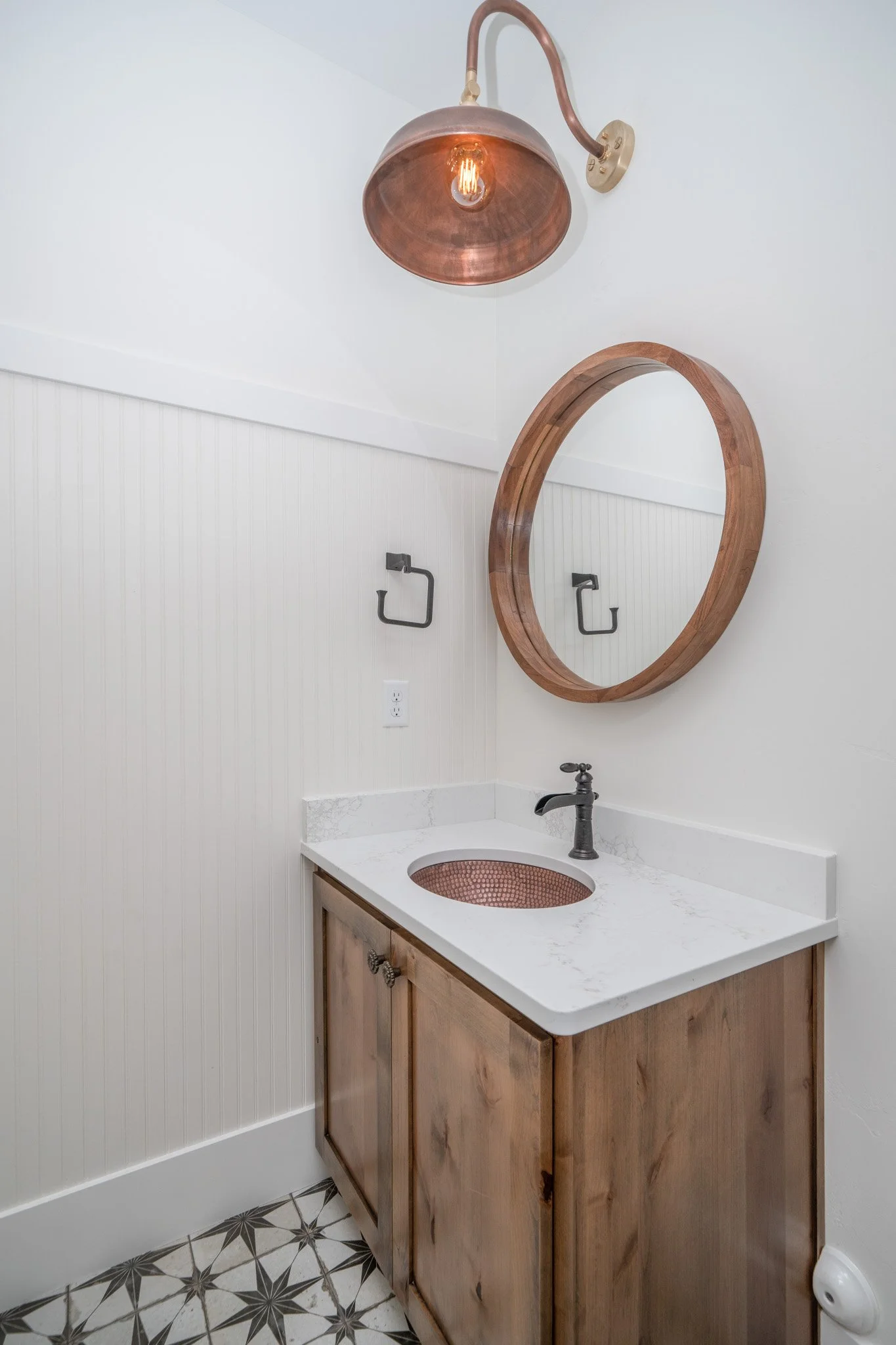 Wood bathroom vanity with a round mirror — JAB Construction’s Modern Rustic custom home in Idaho Falls, Idaho.