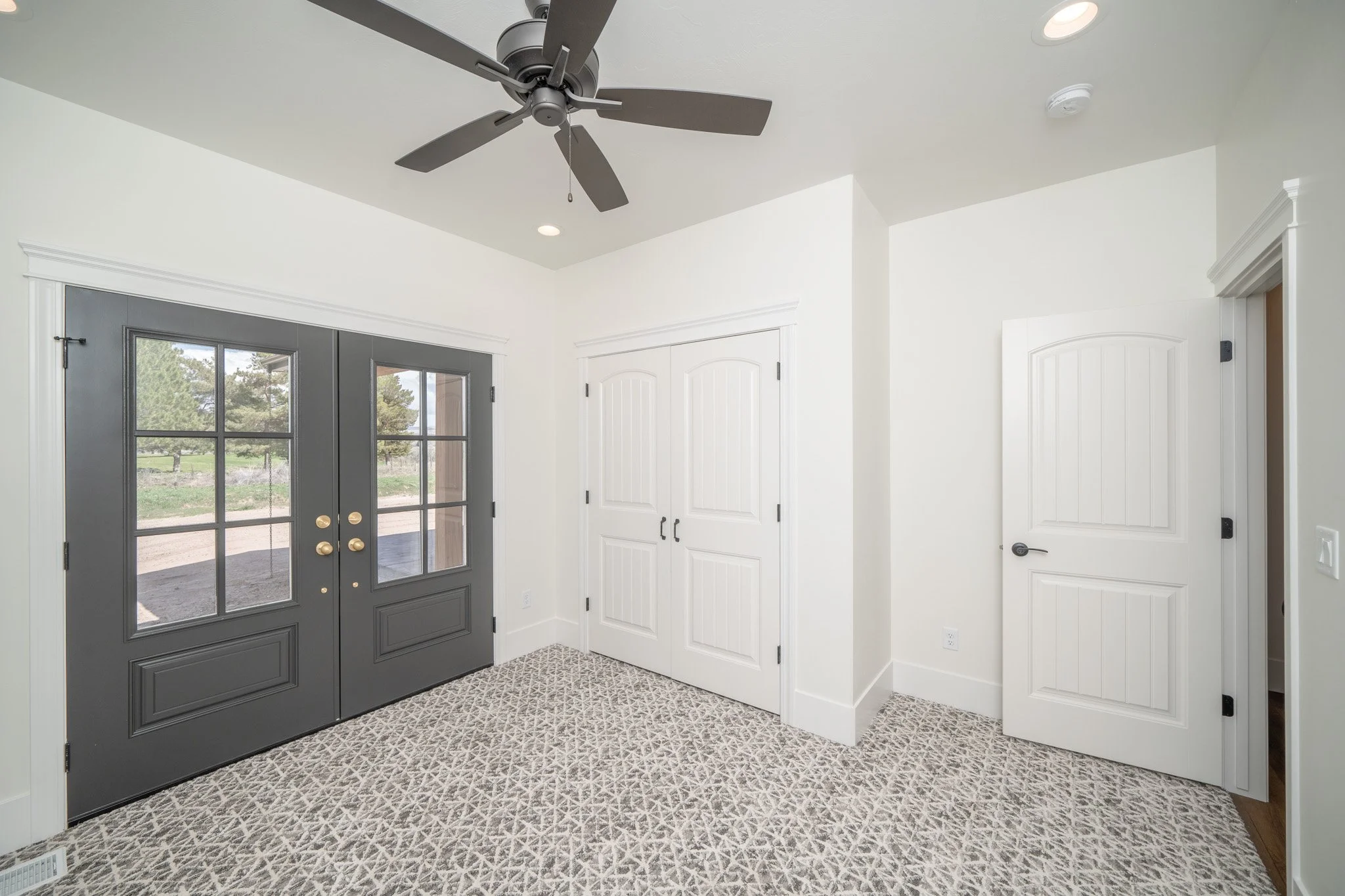 Carpeted bedroom with a ceiling fan and dark accent wall — JAB Construction’s Modern Rustic custom home in Idaho Falls, Idaho.