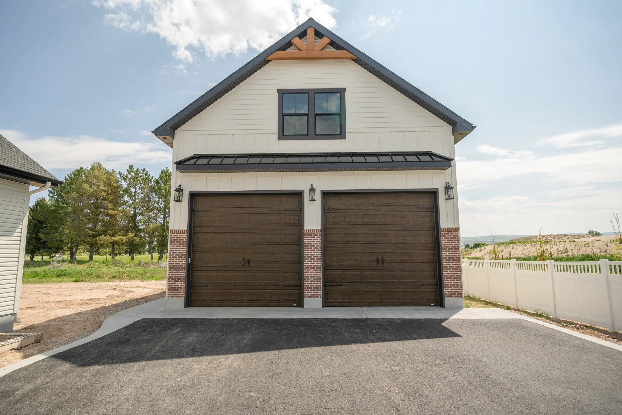 Garage exterior with two wood-look doors and gabled roof — JAB Construction’s Modern Rustic custom home in Idaho Falls, Idaho.