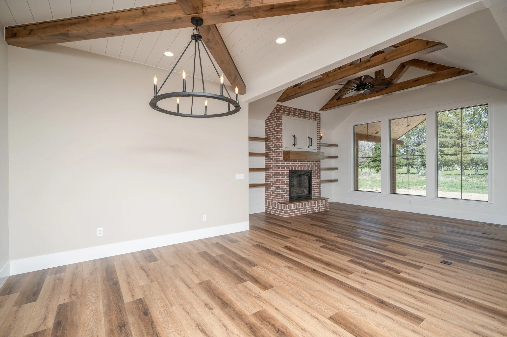 Open living area with wood beams and a brick fireplace — JAB Construction’s Modern Rustic custom home in Idaho Falls, Idaho.