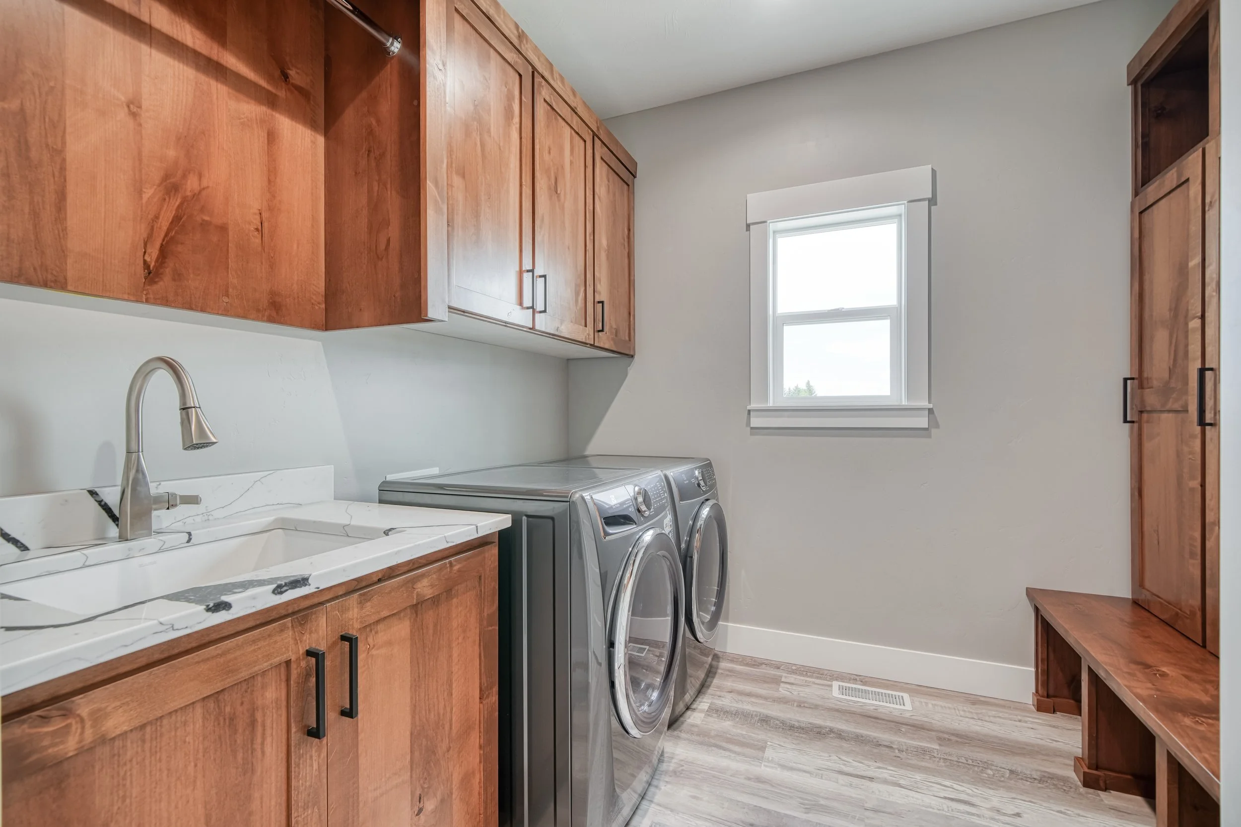 Laundry room with wood cabinets and front-loading appliances — JAB Construction’s Modern Craftsman custom home in Idaho Falls, Idaho.