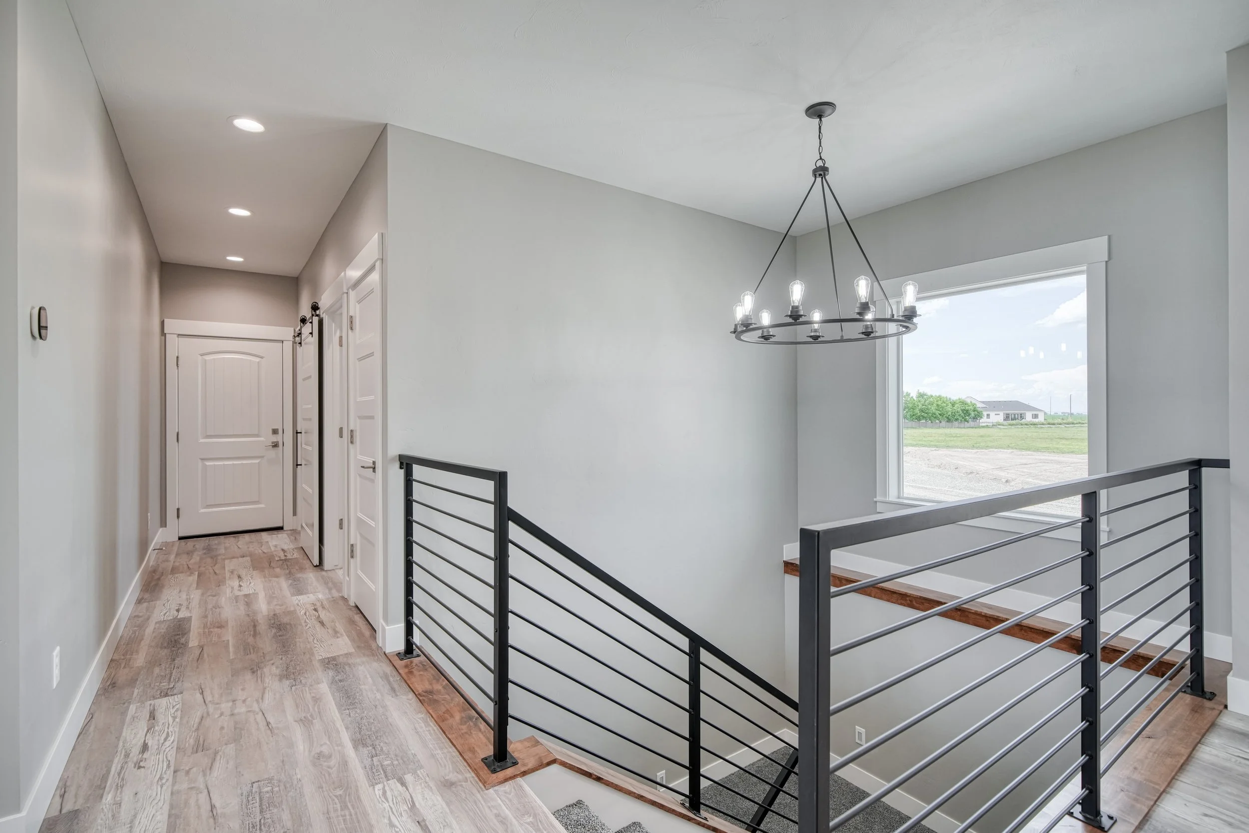 Stair landing with a black metal railing and pendant light — JAB Construction’s Modern Craftsman custom home in Idaho Falls, Idaho.