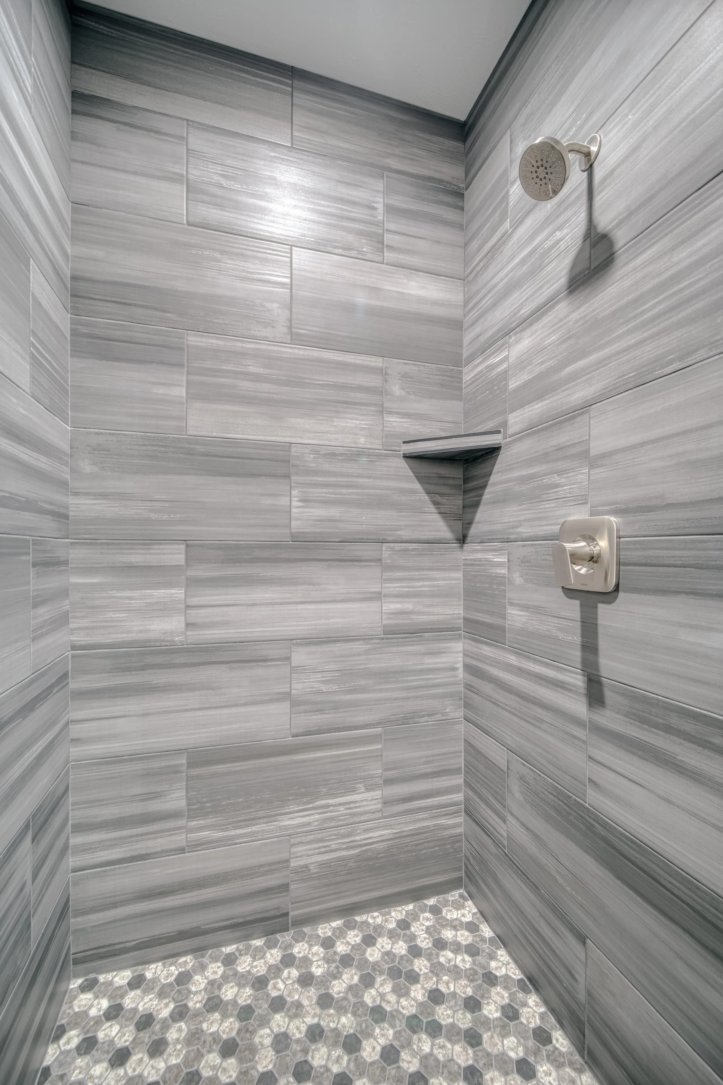 Close view of a tiled shower with built-in shelving — JAB Construction’s Modern Craftsman custom home in Idaho Falls, Idaho.