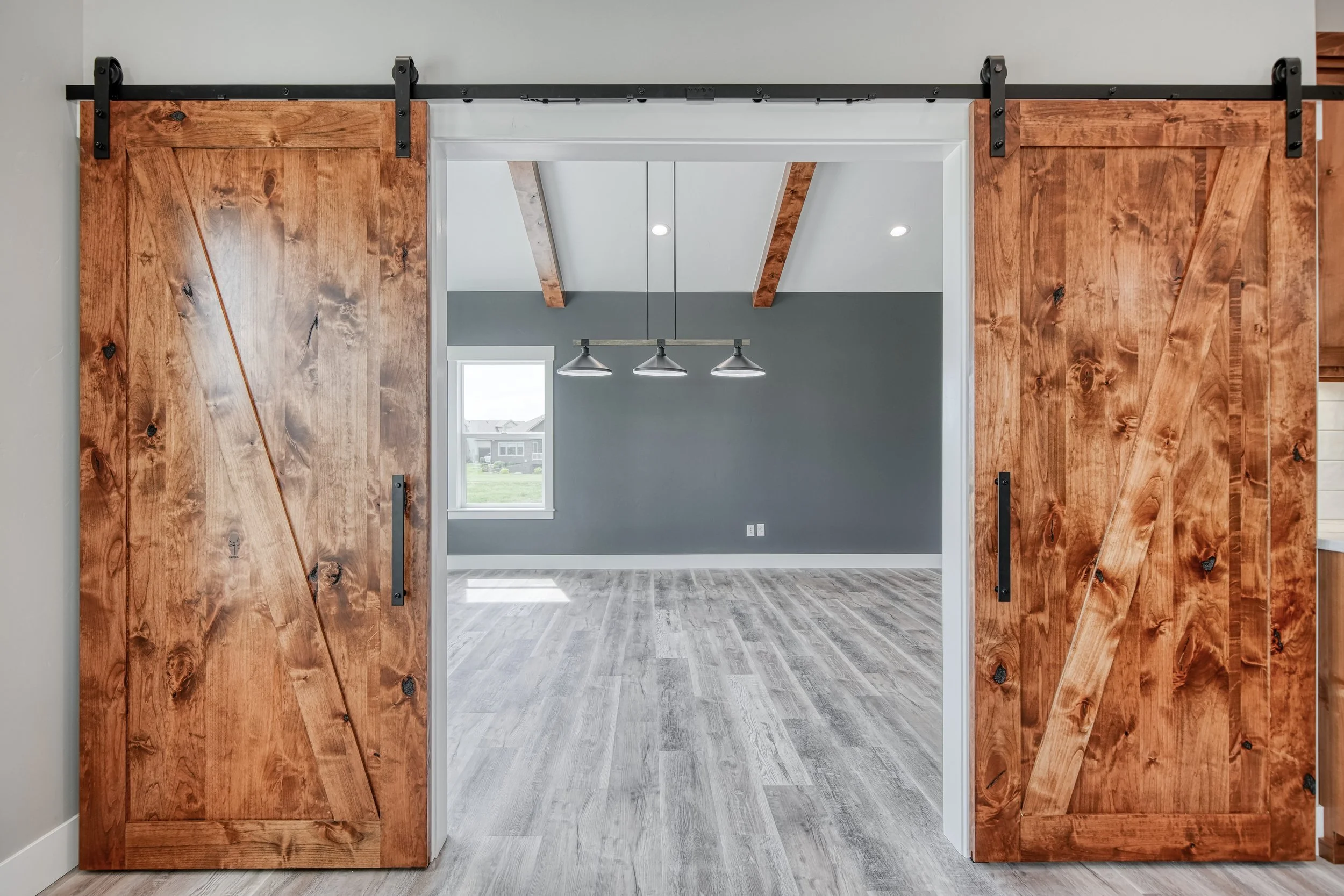 Wood barn doors framing a room with a dark accent wall — JAB Construction’s Modern Craftsman custom home in Idaho Falls, Idaho.