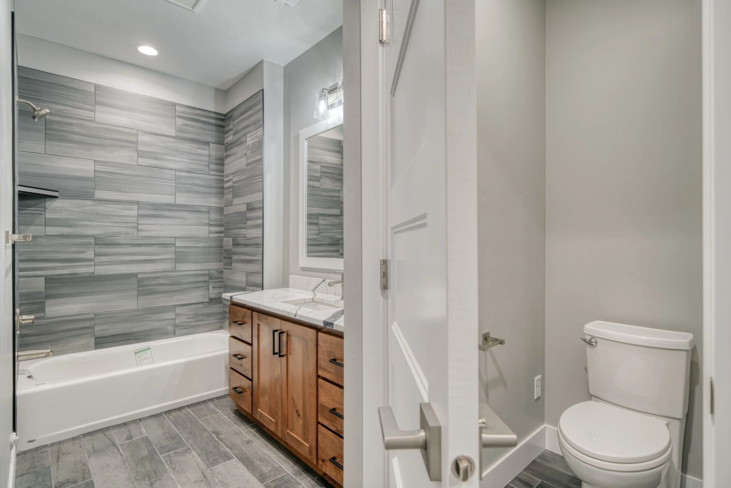 Bathroom with a wood vanity beside a tiled shower — JAB Construction’s Modern Craftsman custom home in Idaho Falls, Idaho.