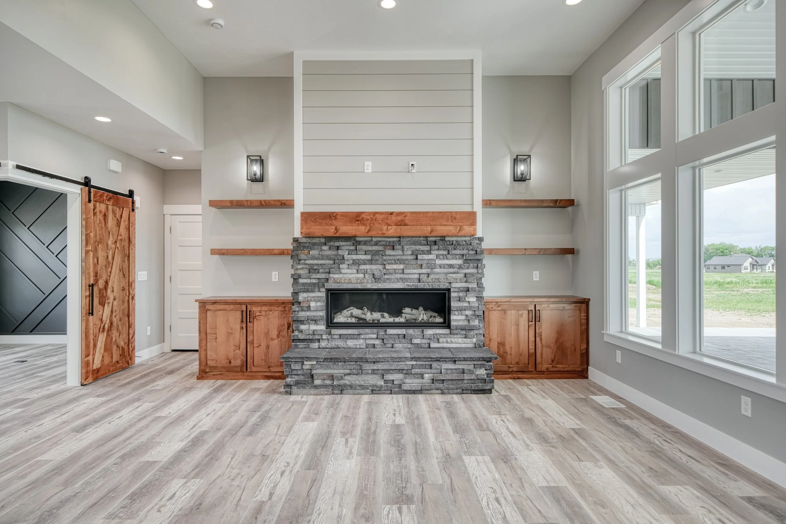 Stone fireplace flanked by built-in wood cabinets — JAB Construction’s Modern Craftsman custom home in Idaho Falls, Idaho.