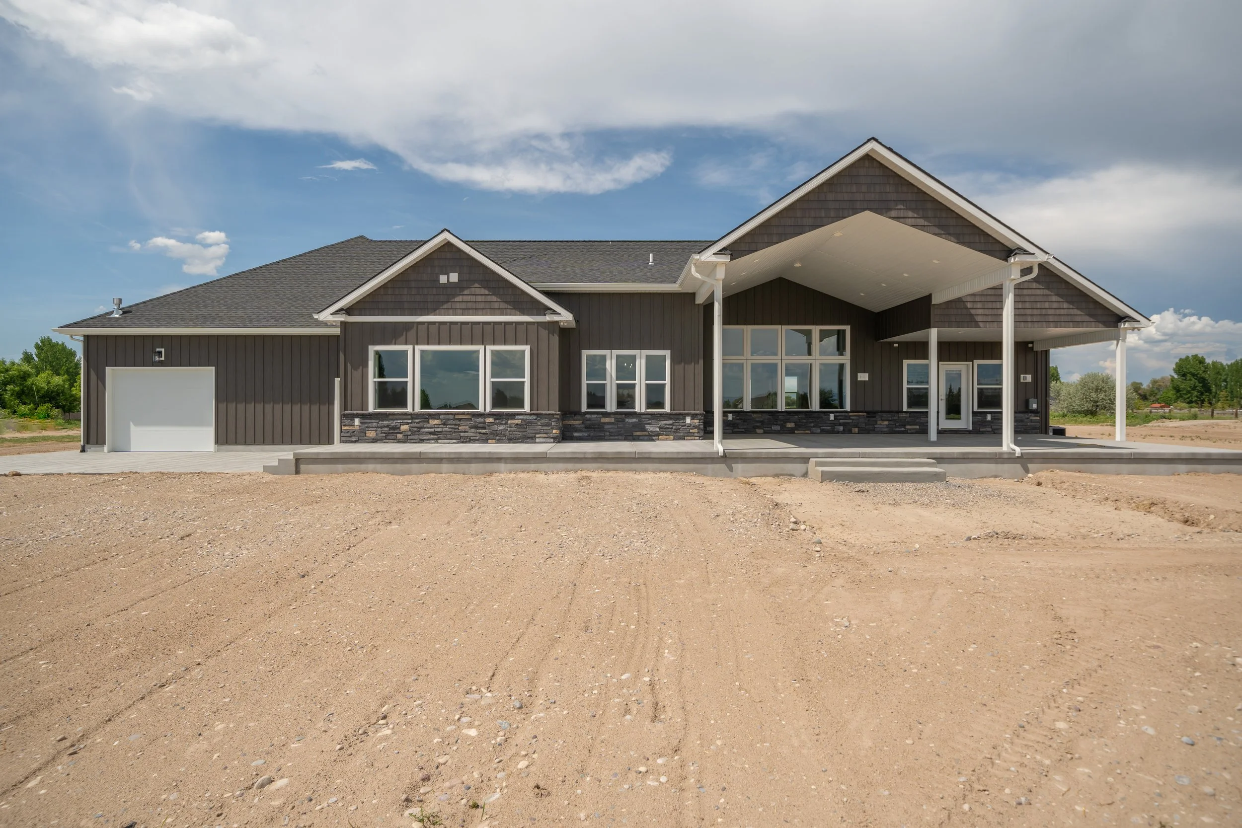 Rear exterior with a covered patio and broad windows — JAB Construction’s Modern Craftsman custom home in Idaho Falls, Idaho.