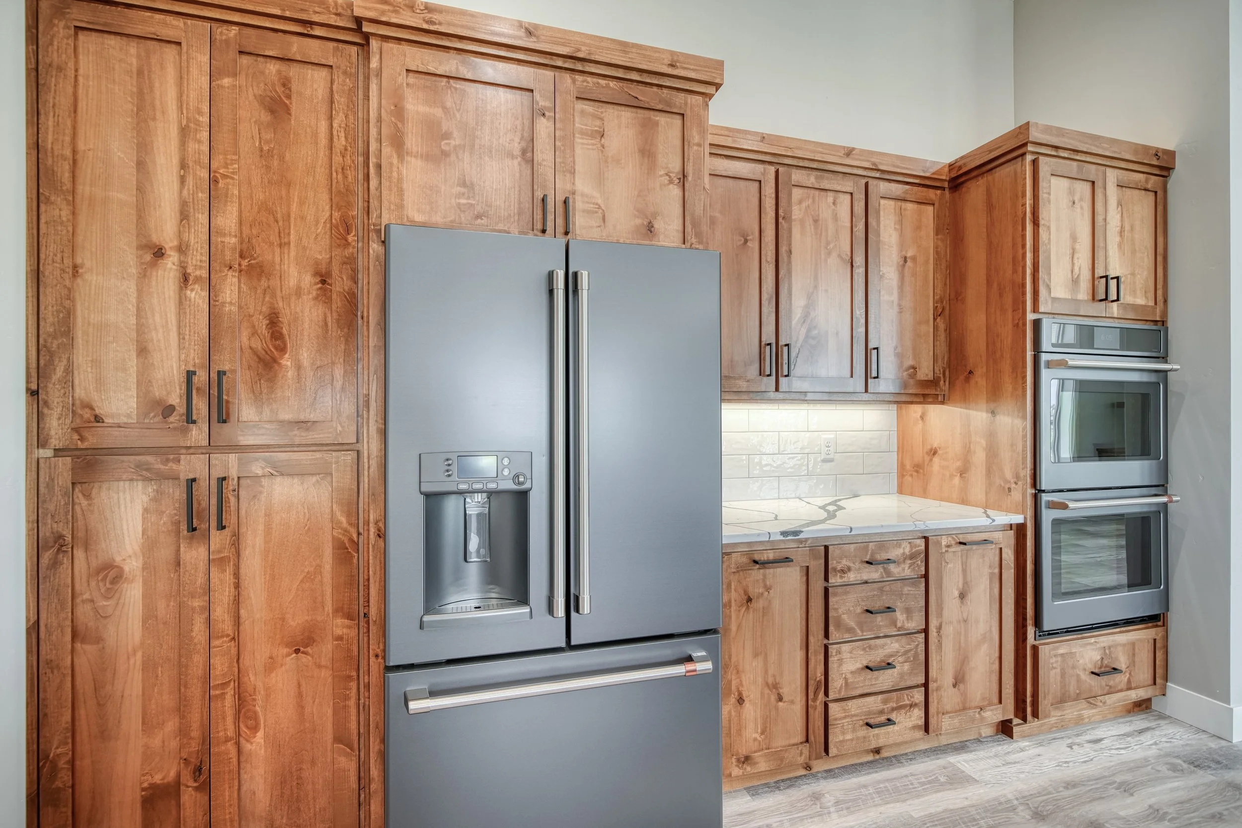 Stainless steel refrigerator framed by wood cabinets — JAB Construction’s Modern Craftsman custom home in Idaho Falls, Idaho.
