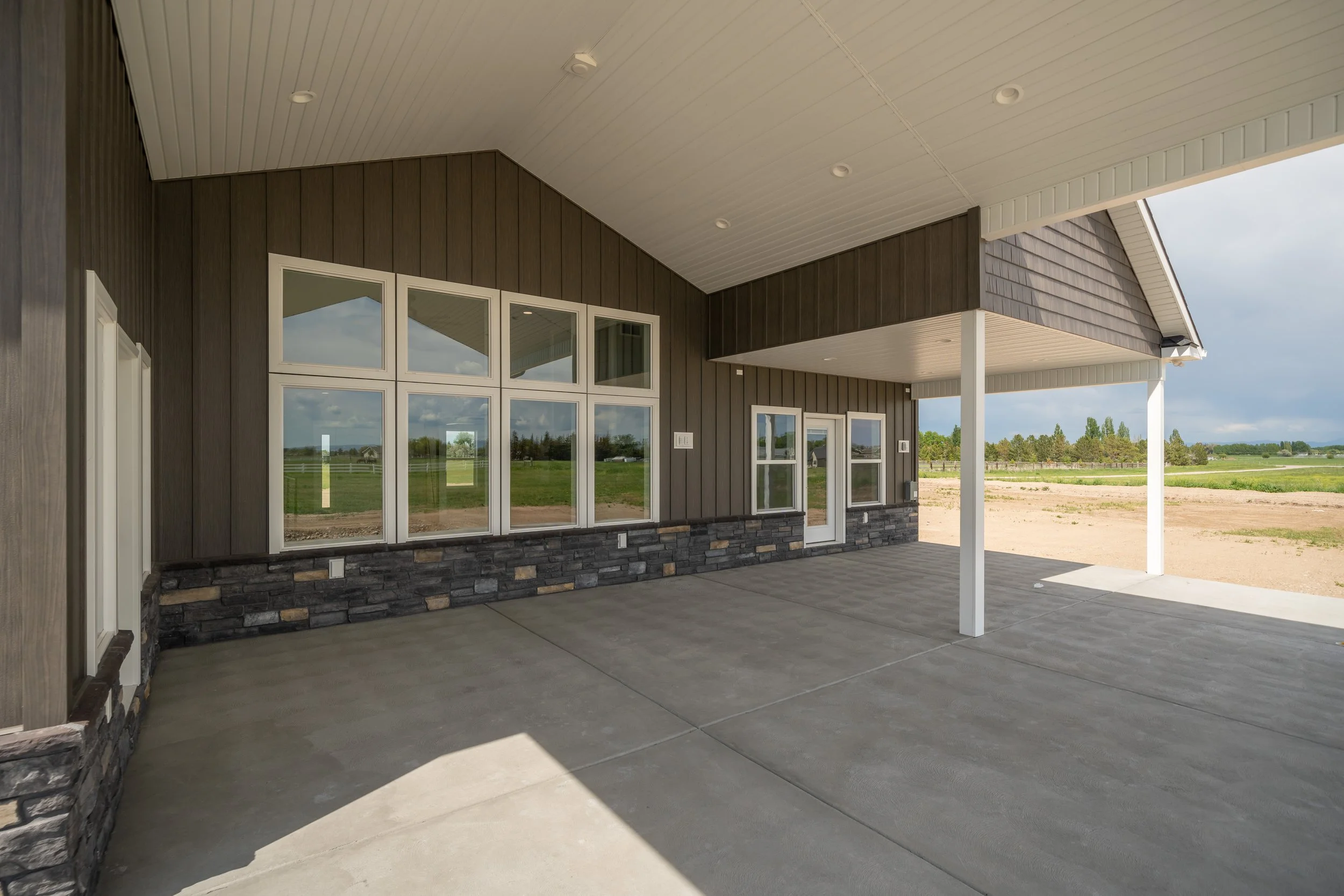 Covered rear patio with white columns and concrete paving — JAB Construction’s Modern Craftsman custom home in Idaho Falls, Idaho.