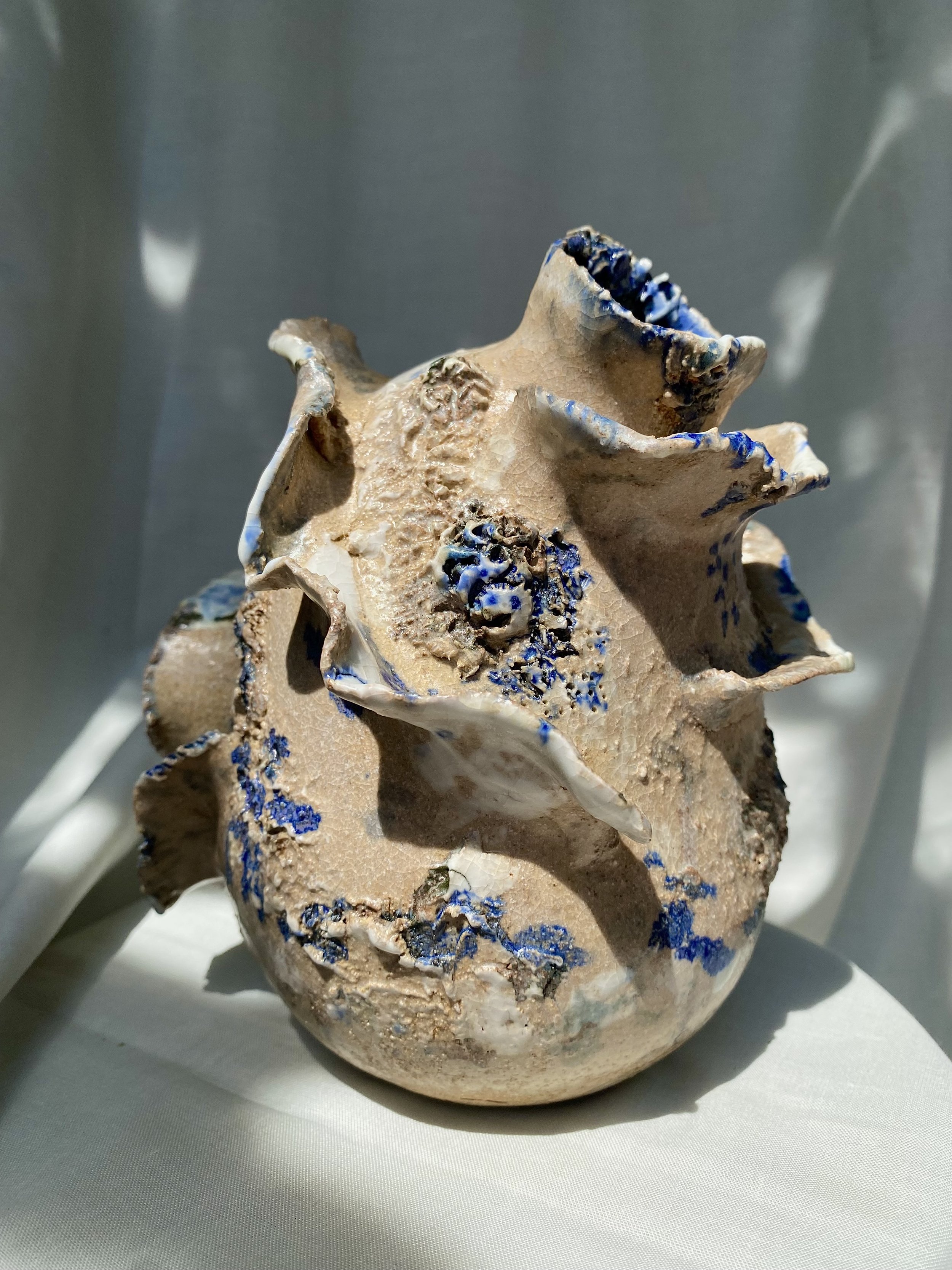 A ceramic sculpture inspired by the sea. Curved accents are added to the large piece. Featuring splashes of blue glaze and porcelain slip.