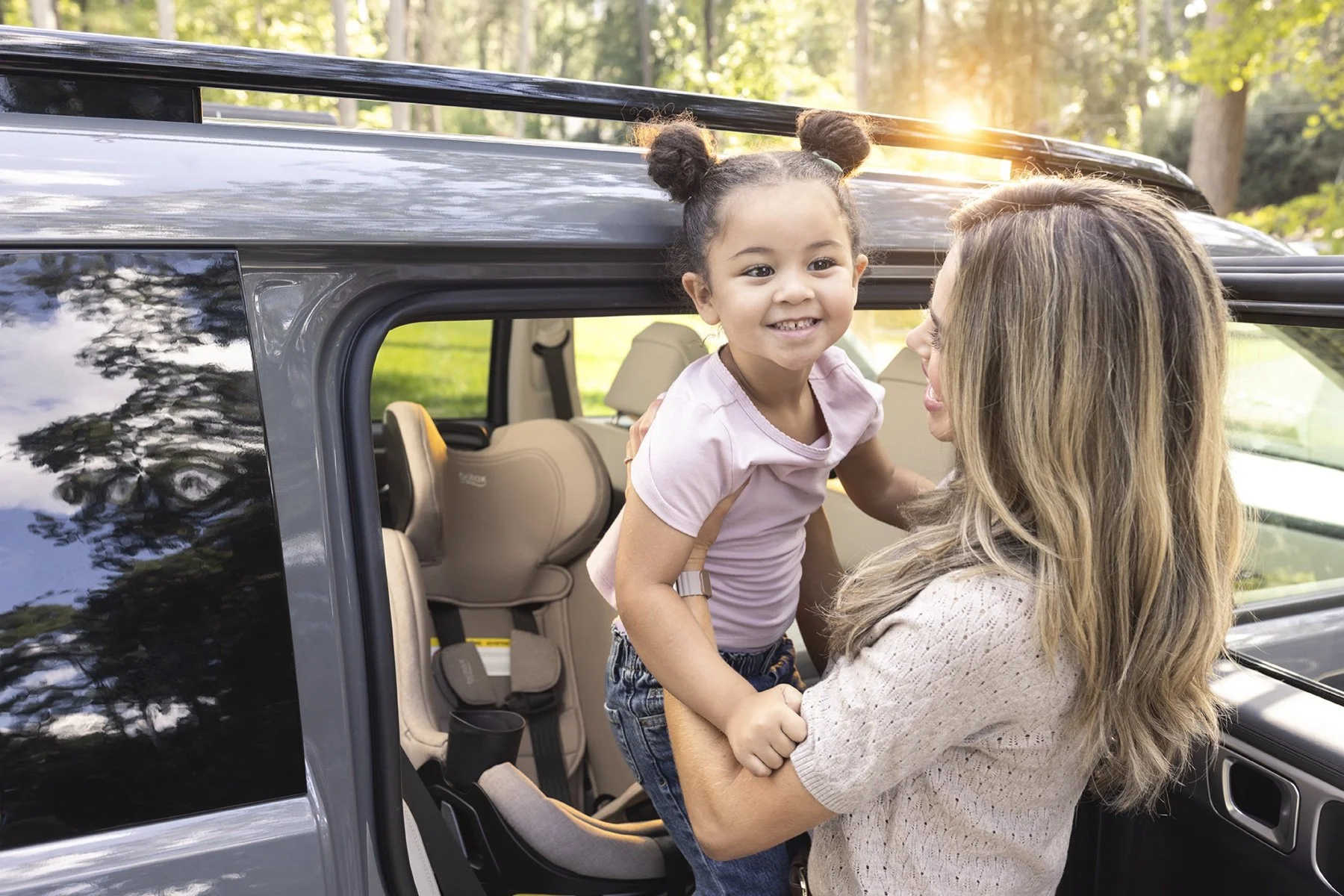 Mother helping an older child into the Britax Galaxy360 rotating car seat.