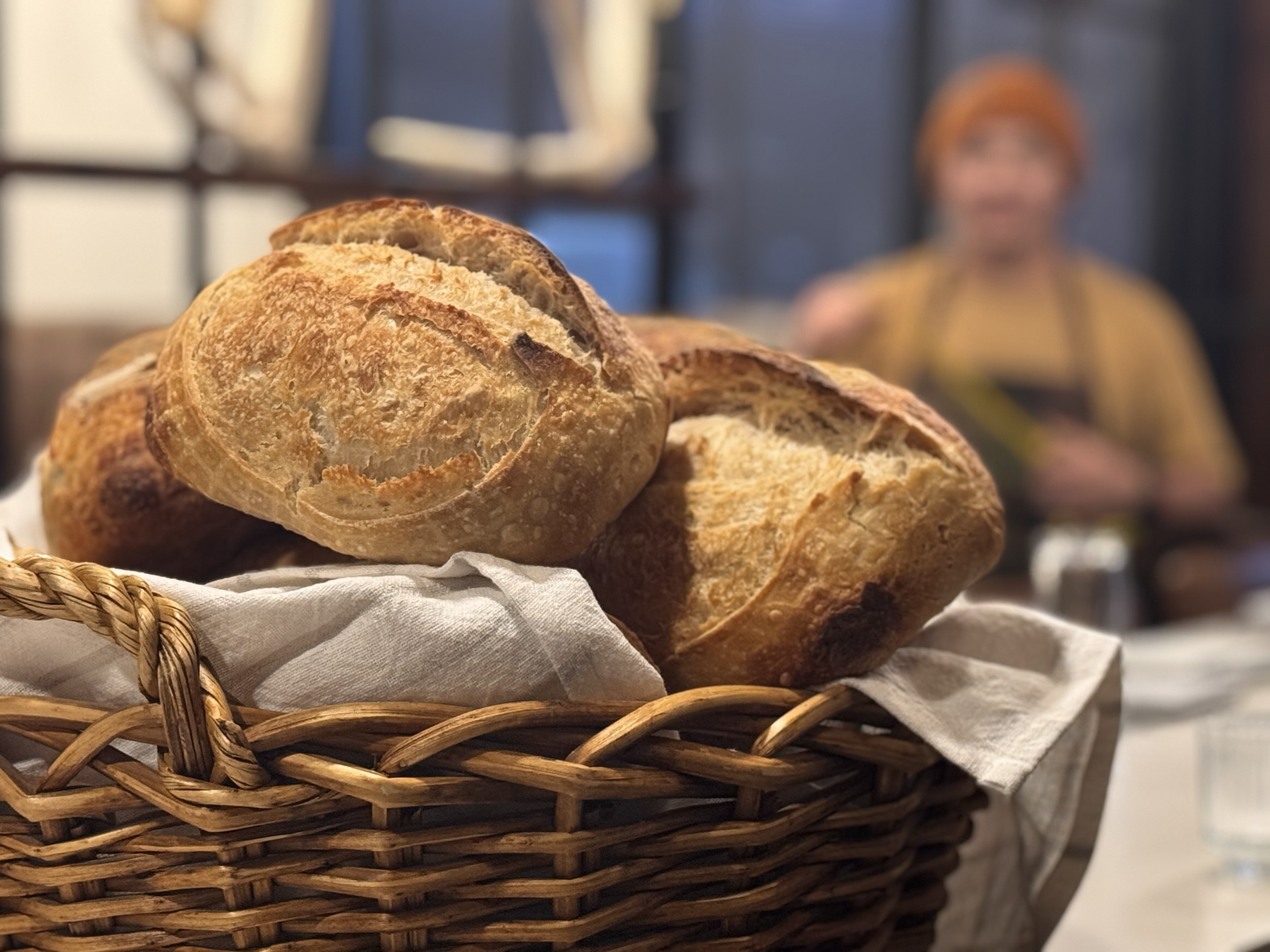 Close-up of a basket with freshly baked bread rolls on a white cloth.
