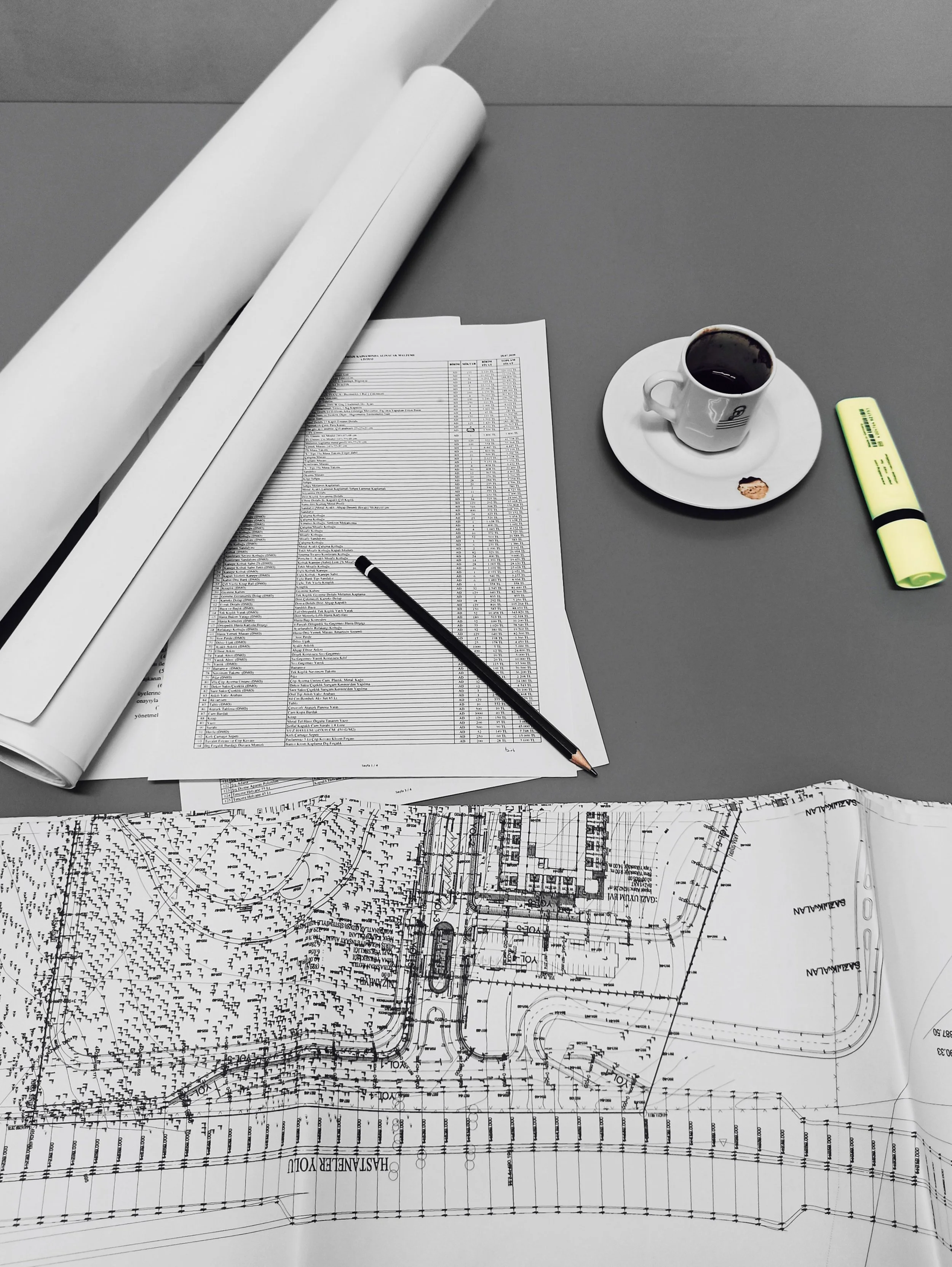 Construction drawings and plans on a work table with a pencil and highlighter