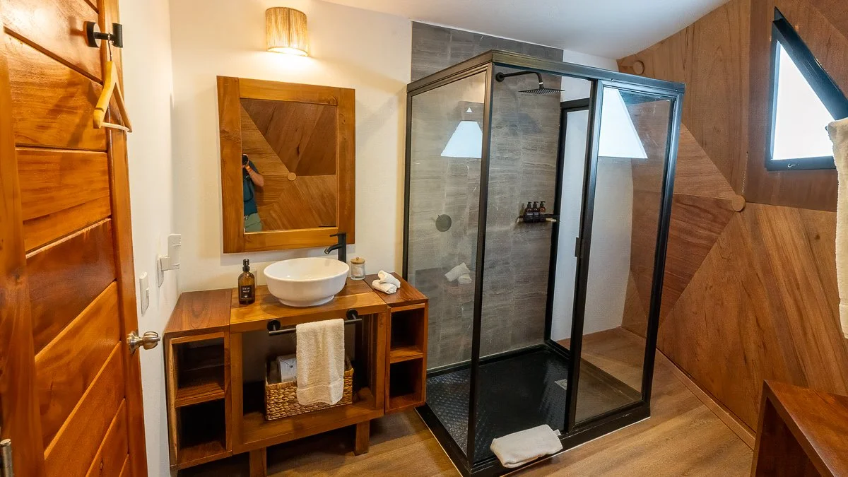 Bathroom with wooden accents, a glass shower enclosure, a vessel sink on a wooden vanity, and a mirror.