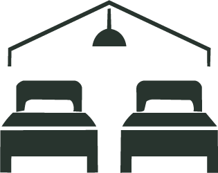 Two beds with pillows in a room with a hanging ceiling light