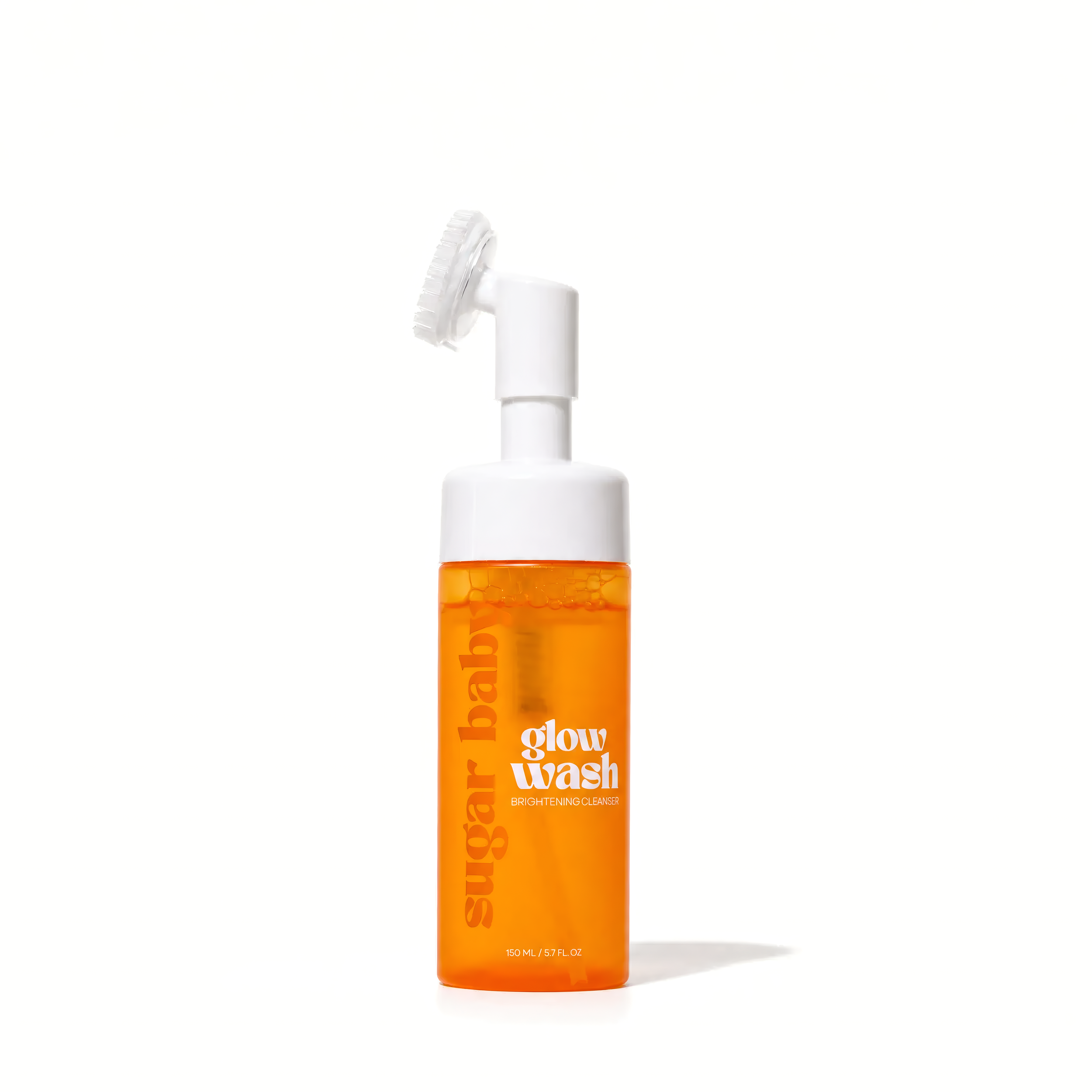 Orange bottle of clarifying facial cleanser with white spray top and brush applicator, labeled 'brightening cleanse' and 'glow wash'.