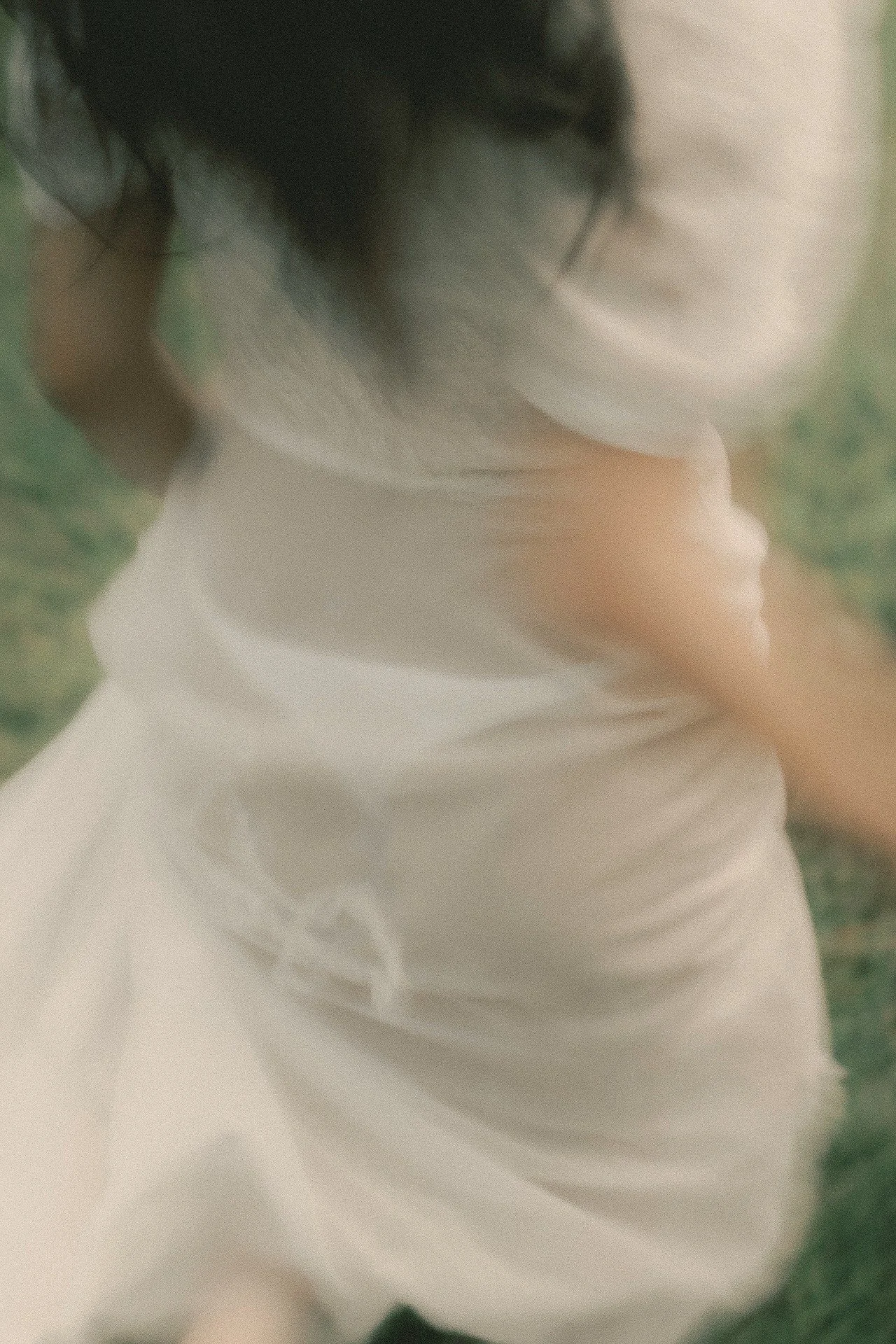 A woman in a flowing white dress surrounded by lush tropical greenery in Malaysia.