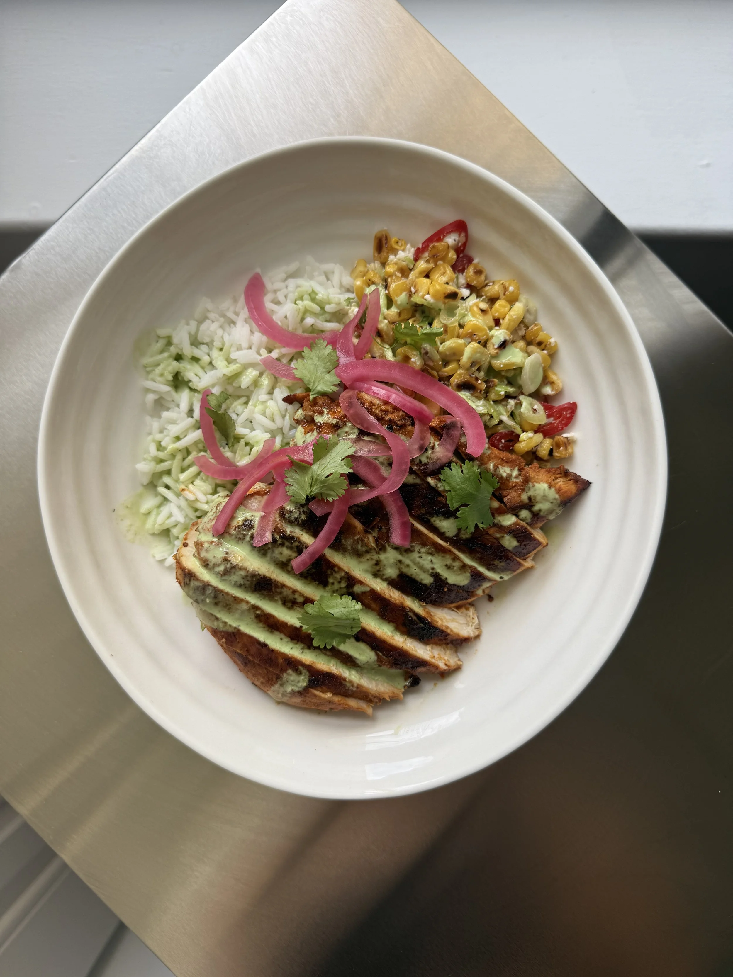 Grilled chipotle chicken with rice and sweetcorn salsa. Topped with pickled red onions and a cilantro and lime crema