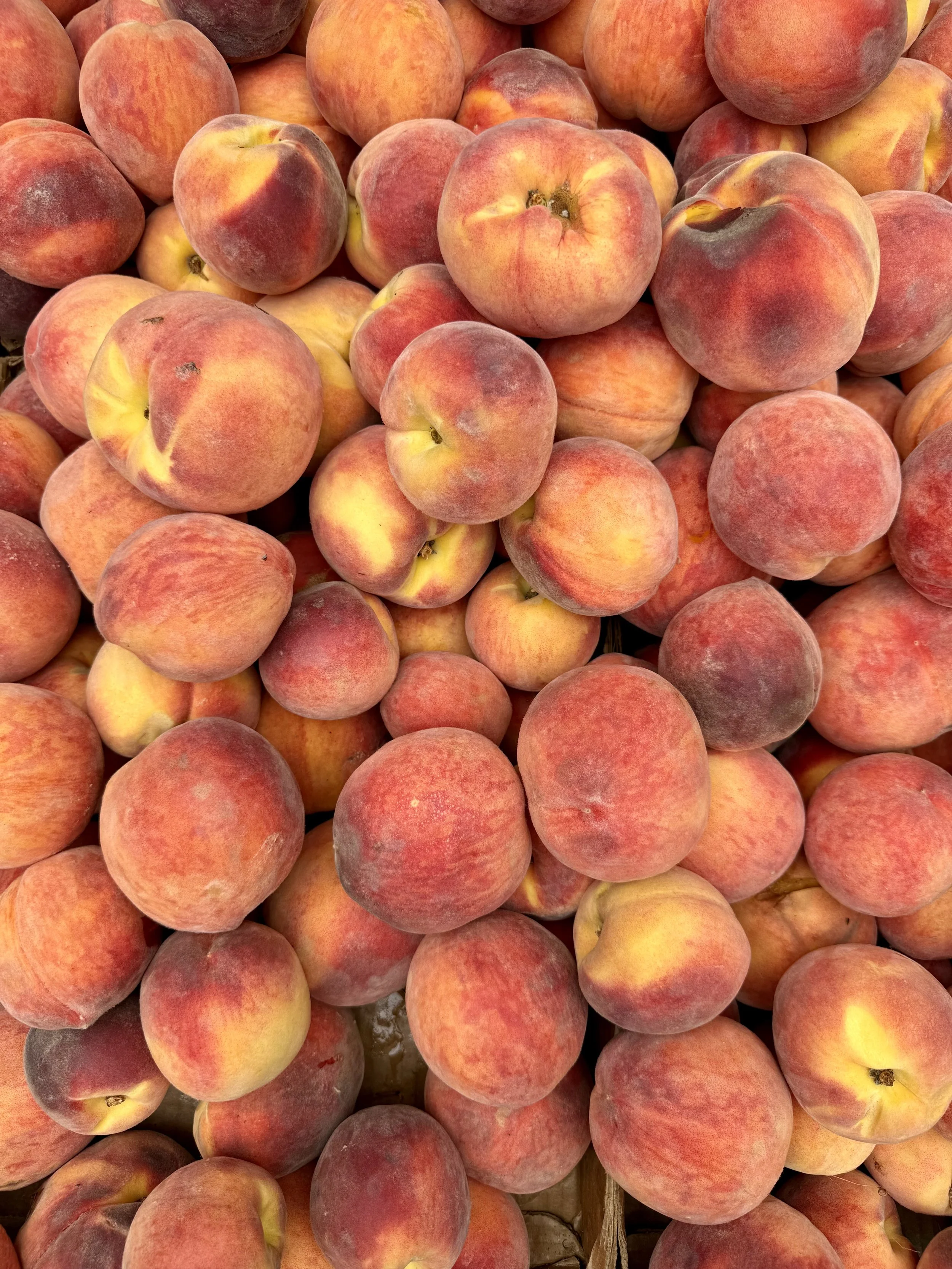 A close-up of a large pile of peaches