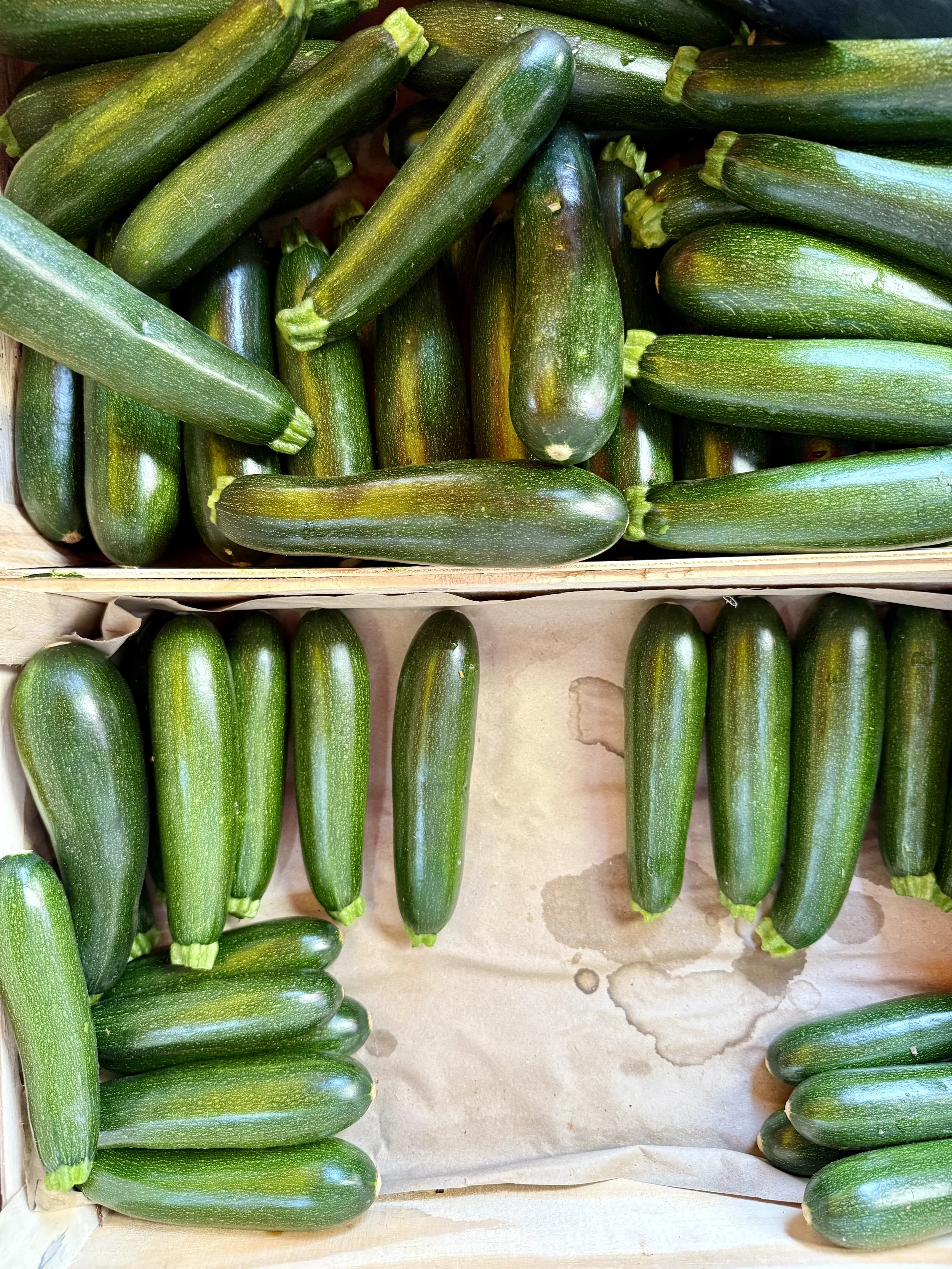 Fresh zucchinis arranged in a wooden crate