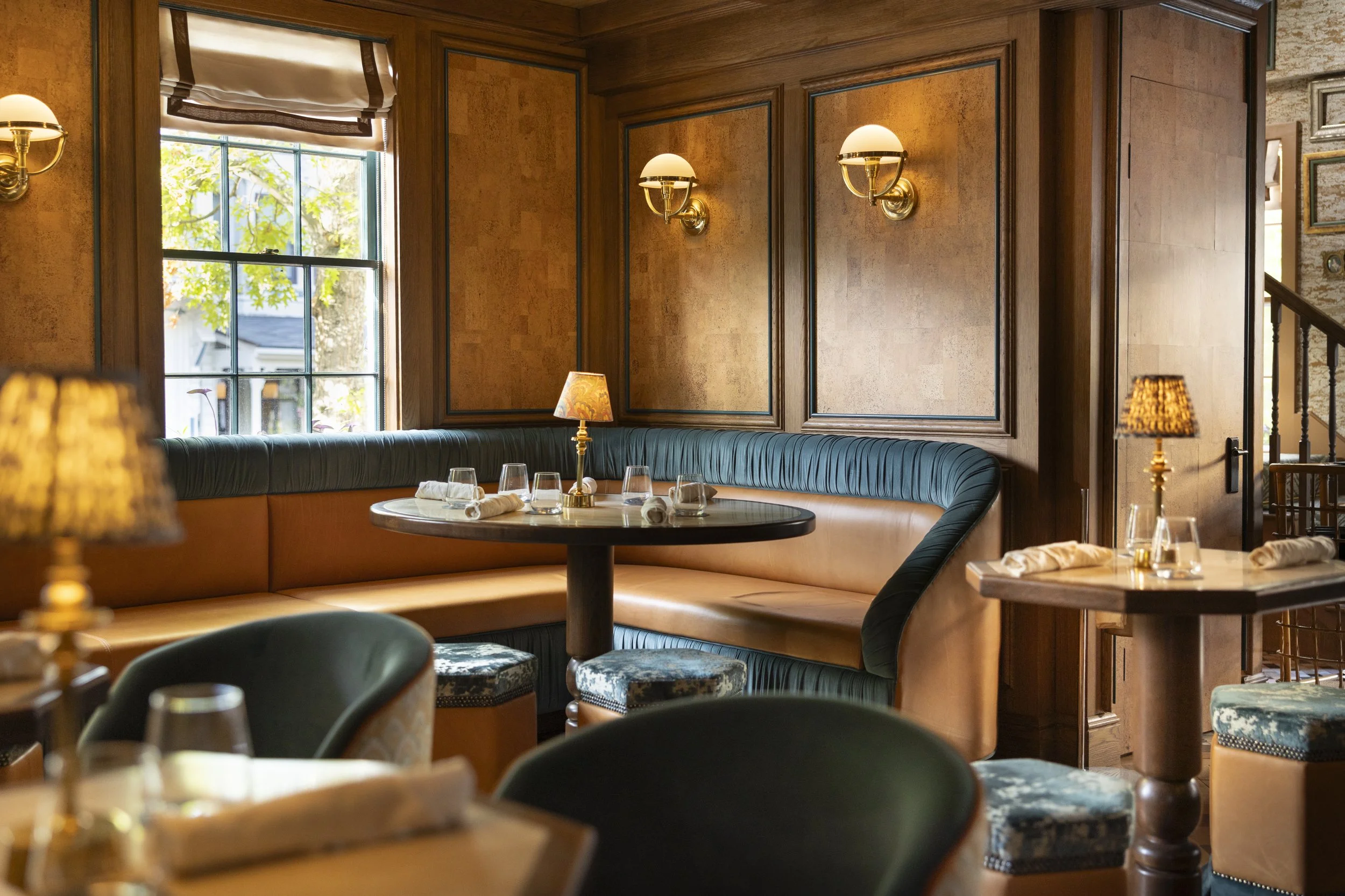 Interior of Billie's Nantucket restaurant featuring cork-paneled walls, warm lighting and intimate banquette seating.