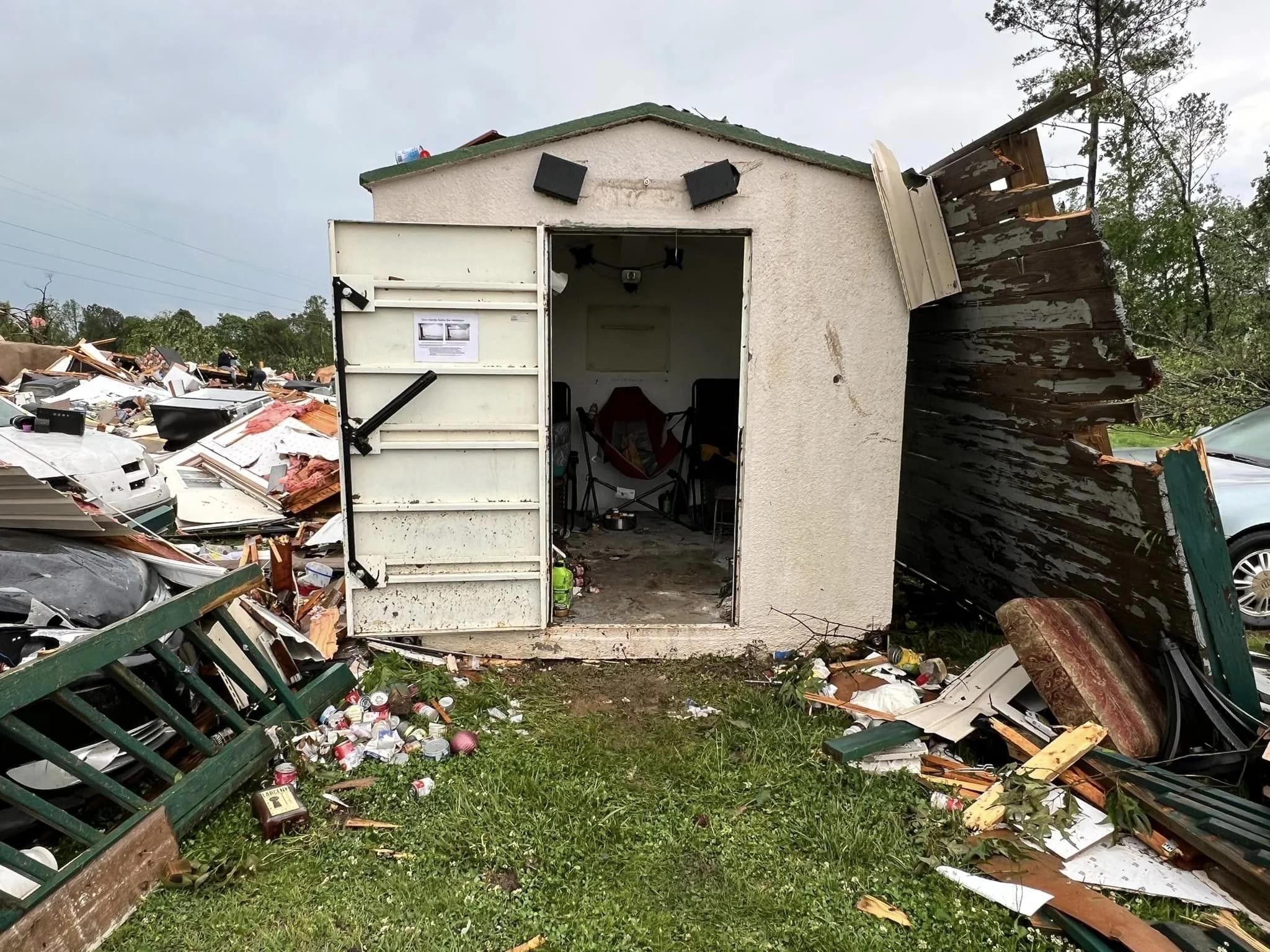intact storm shelter amid a large debris field