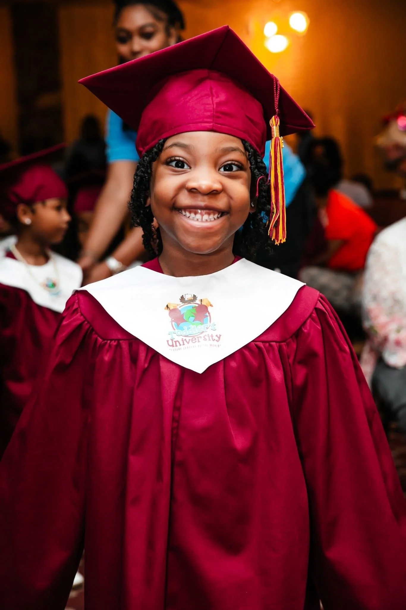 Student in graduation cap and gown smiling for the camera at Toddler’s University’s 2026 graduation ceremony.