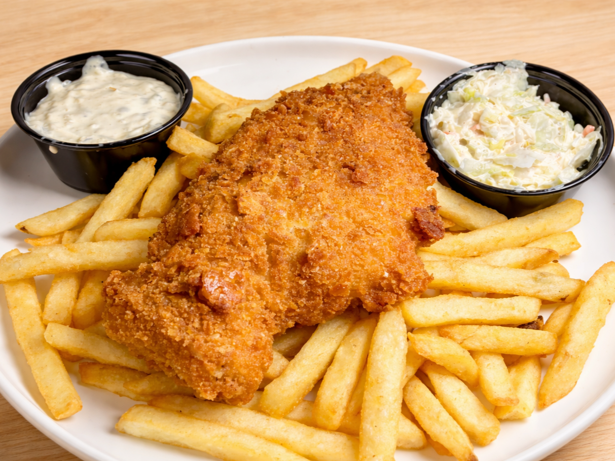 Fried fish fillet with French fries, tartar sauce, and coleslaw on a white plate.