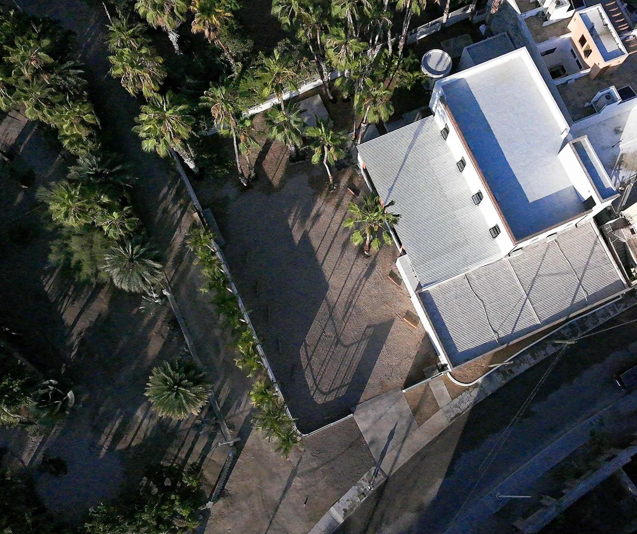 An aerial view of rooftops, trees, and streets in a city neighborhood at night.