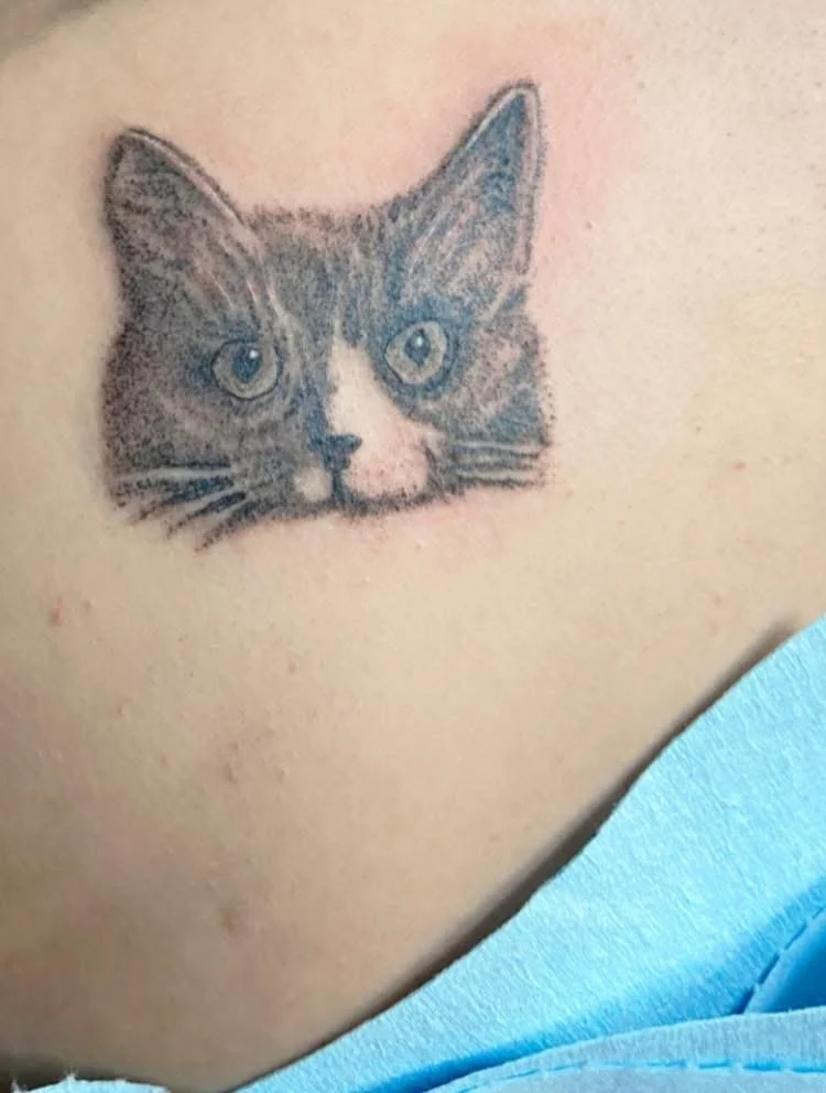 Close-up of a tattoo of a cat's face on skin.