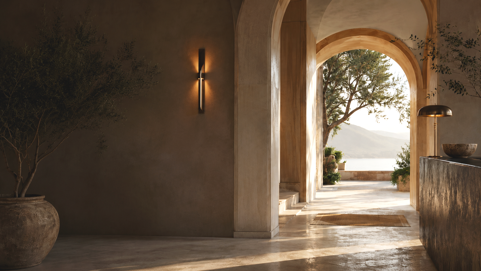 Interior view of a modern space with a large arched doorway opening to an outdoor patio and scenic view of trees and mountains, decorated with warm lighting and natural elements.