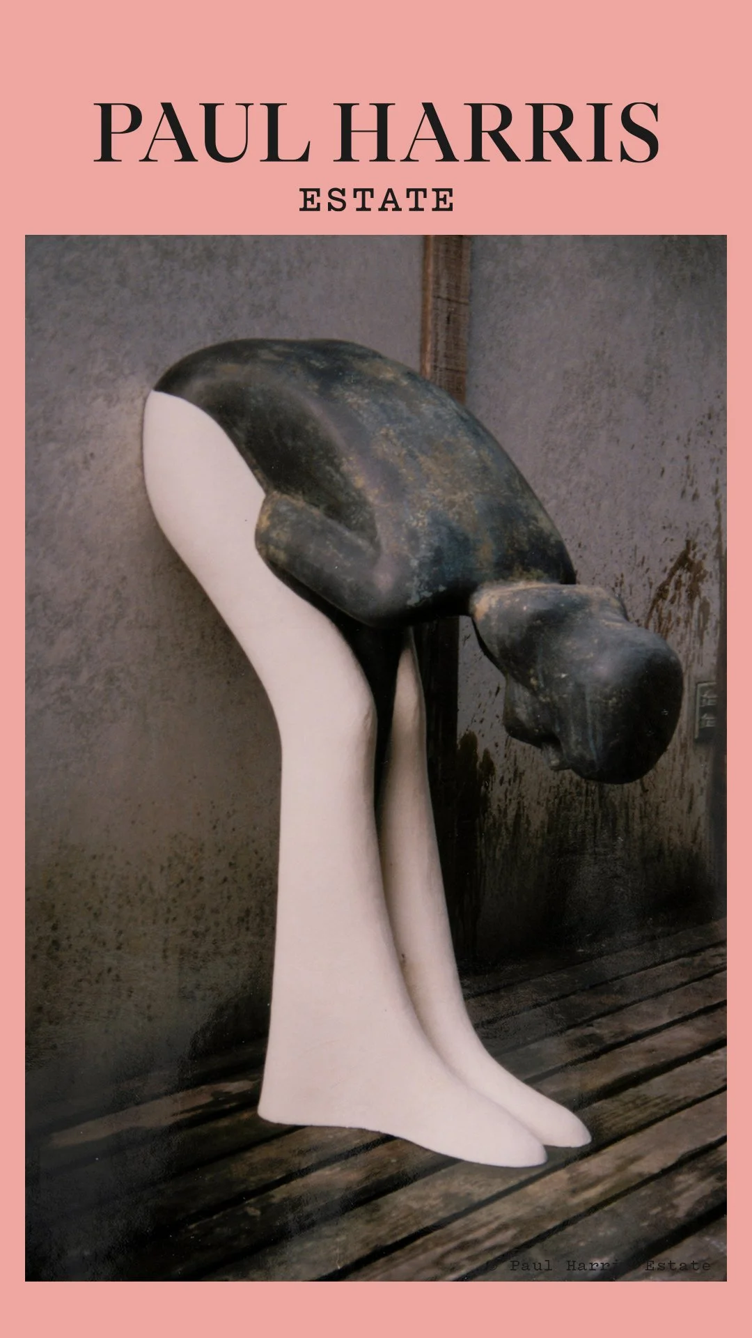 A sculpture of black and white high-heeled shoes with elongated heels, with one shoe being held by a white hand sculpture, set against a dark textured wall.