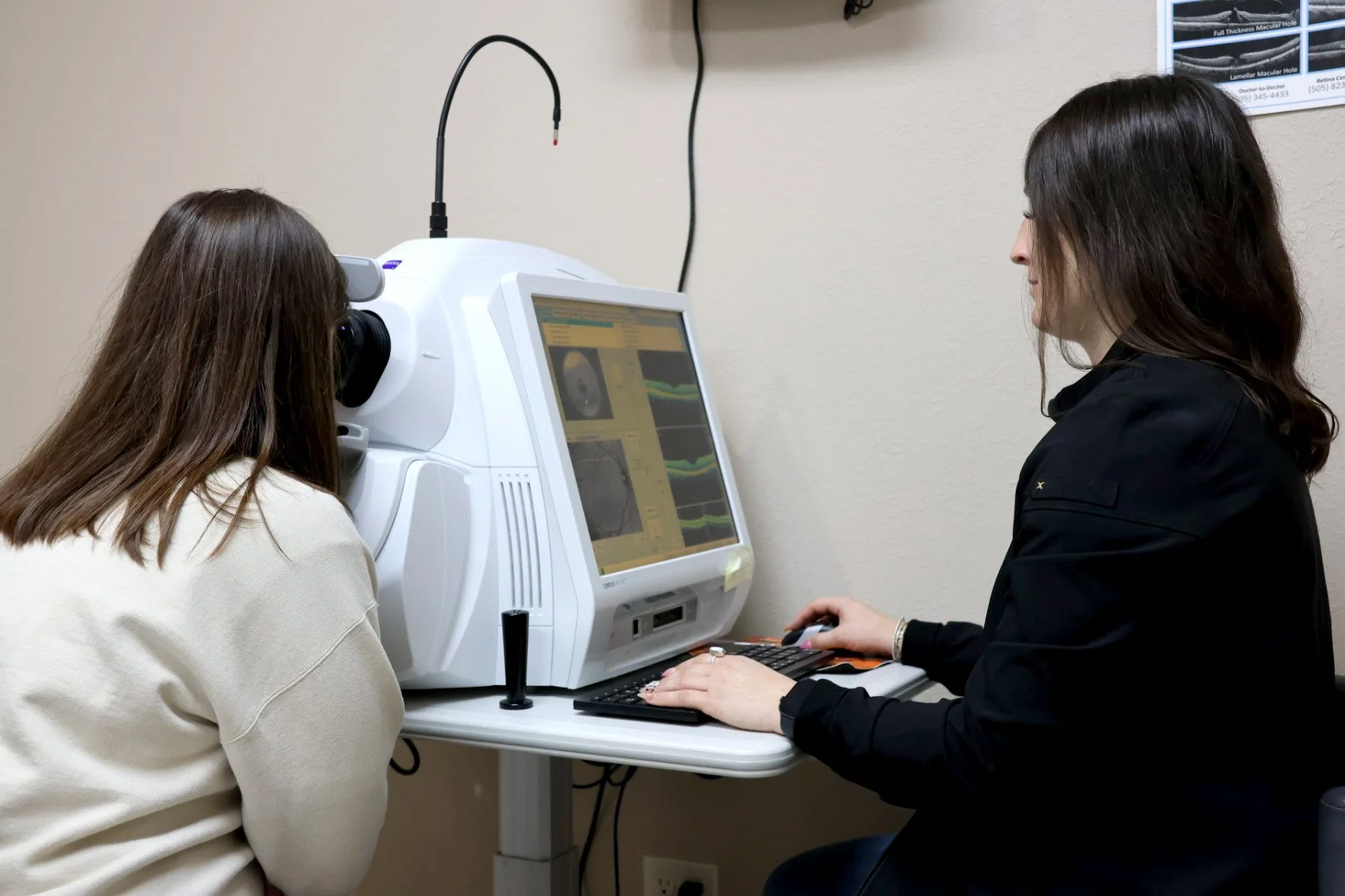 An eye technician runs tests on a patient using a machine. 