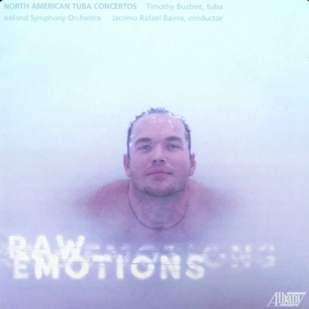 A man with his head and shoulders submerged in a bath or tub, with text at the top indicating a music concert and conductor, and at the bottom the words 'RAW EMOTIONS' and 'Albany'.