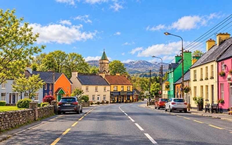 Sneem village on the Ring of Kerry offers a colourful place to pause, with welcoming streets, traditional shopfronts and mountain scenery framing the village.