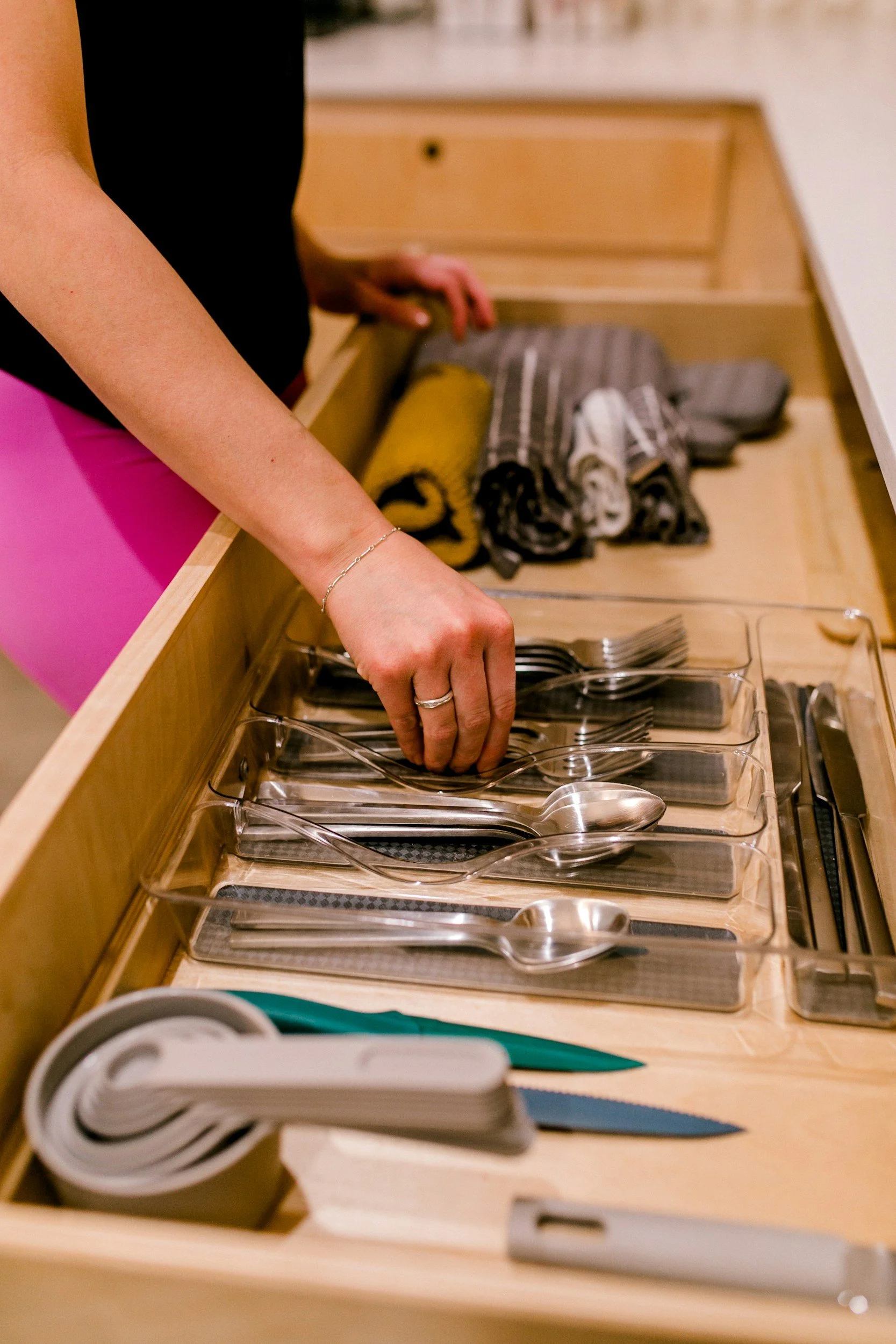 Woman arranging silverware in a kitchen drawer.