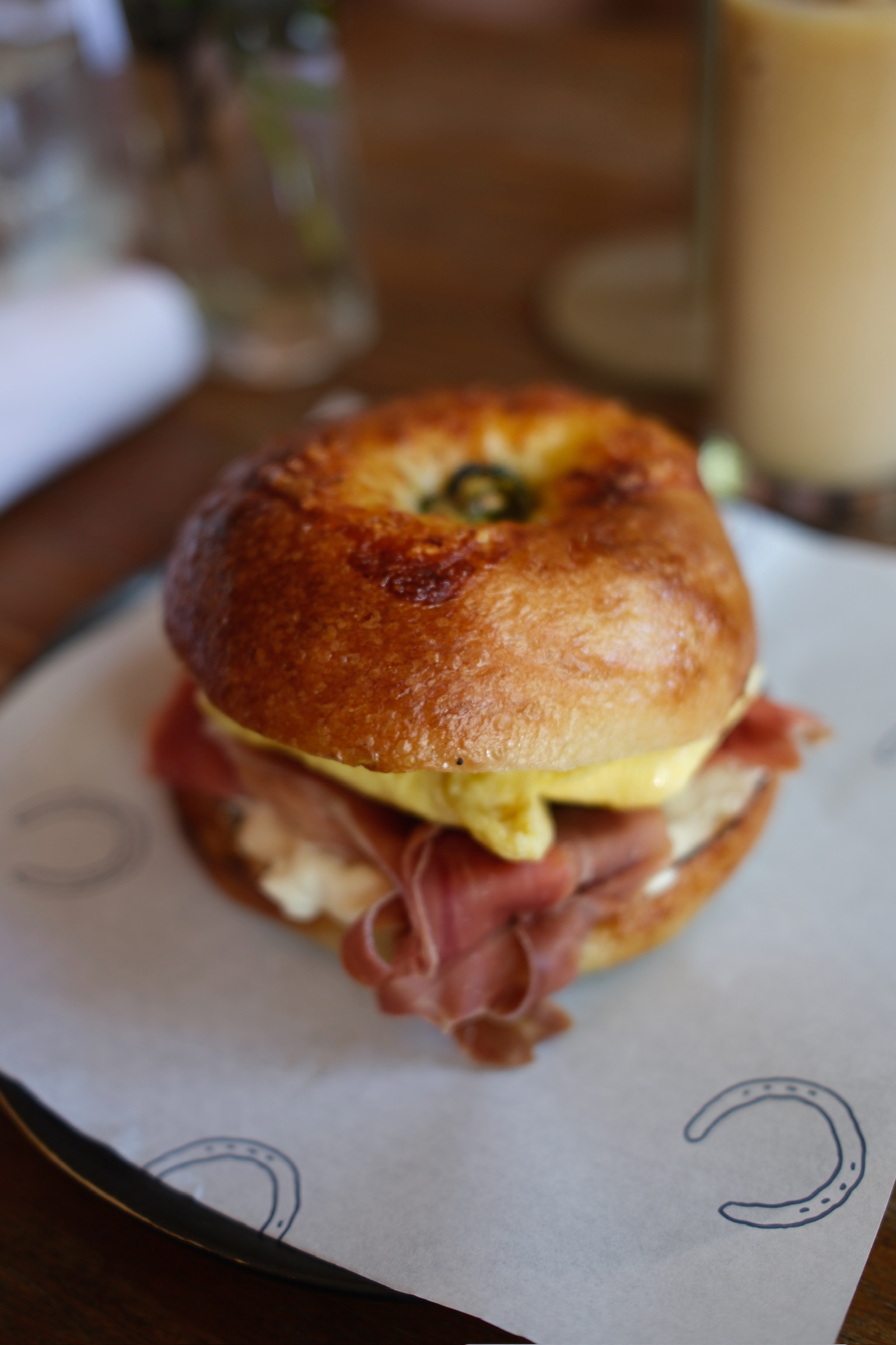 Close-up of a breakfast bagel sandwich with bacon, egg, and cheese.