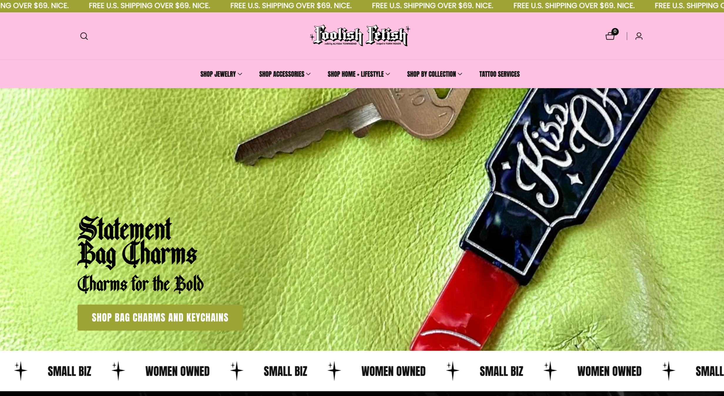 Close-up of jewelry and accessories on a bright green textured surface. The jewelry includes a key and a bag charm with the word 'Fetish' in a gothic font, and the text overlay describes bag charms and keychains for the bold.