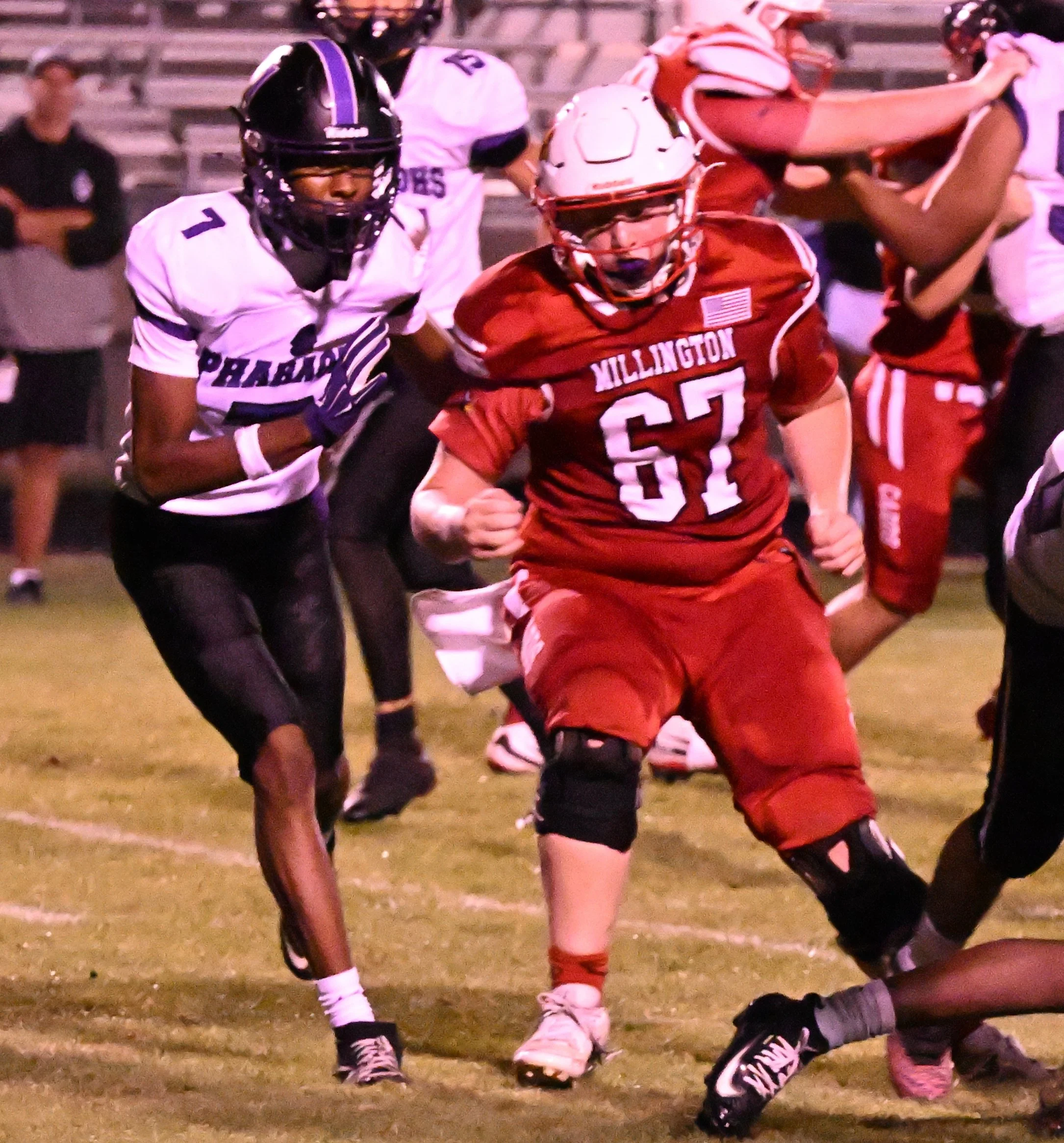 Football players in action during a game, wearing uniforms and helmets, on a grassy field.