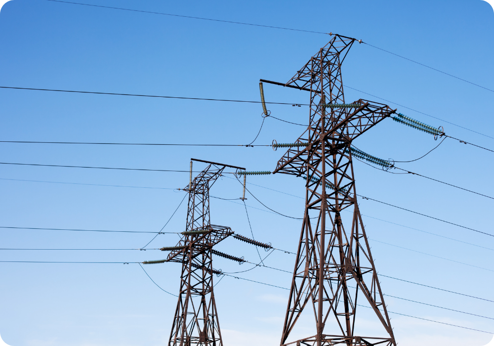Two electrical transmission towers with power lines against a clear blue sky.