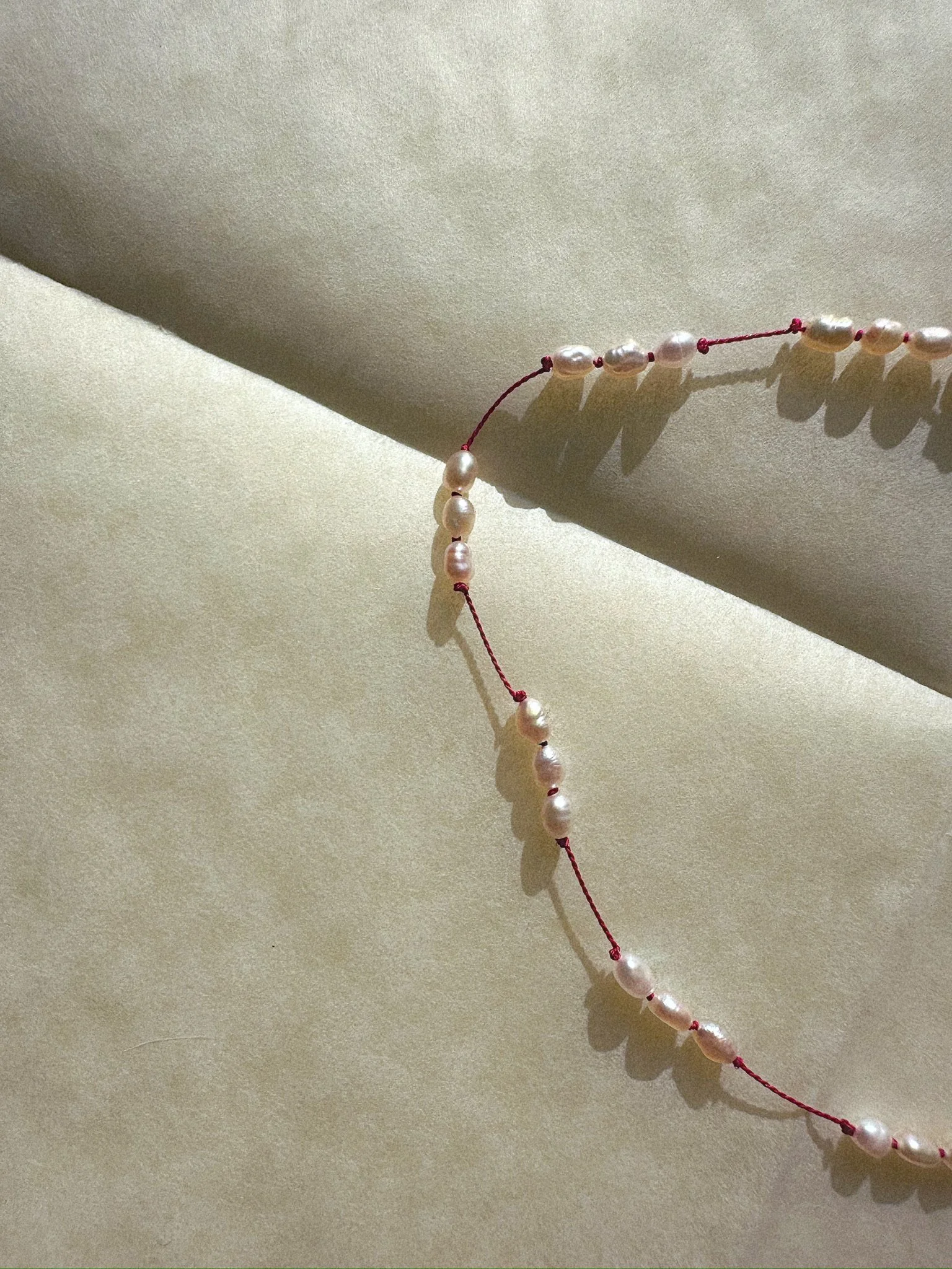 Anklet with tiny pearls on red silk with silver clasp