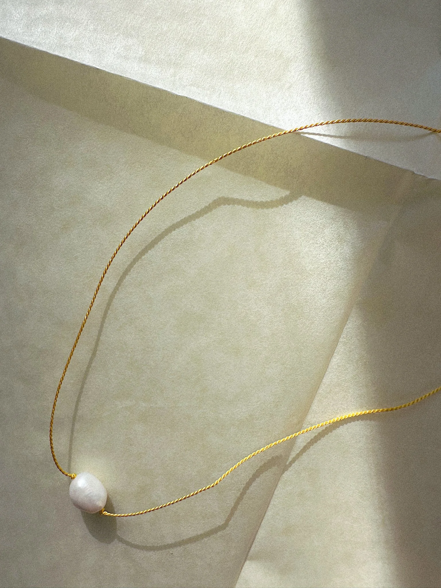 Single freshwater pearl necklace hand-knotted on colorful silk thread close up
