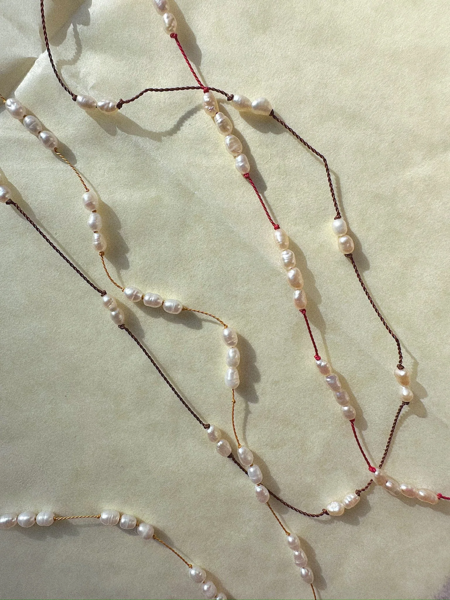 multiple knotted pearl necklaces red, brown, yellow silk
