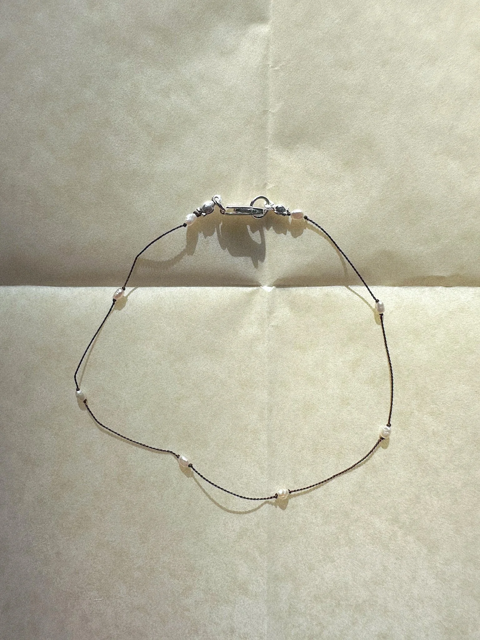 Anklet with tiny pearls knotted on brown silk and silver clasp
